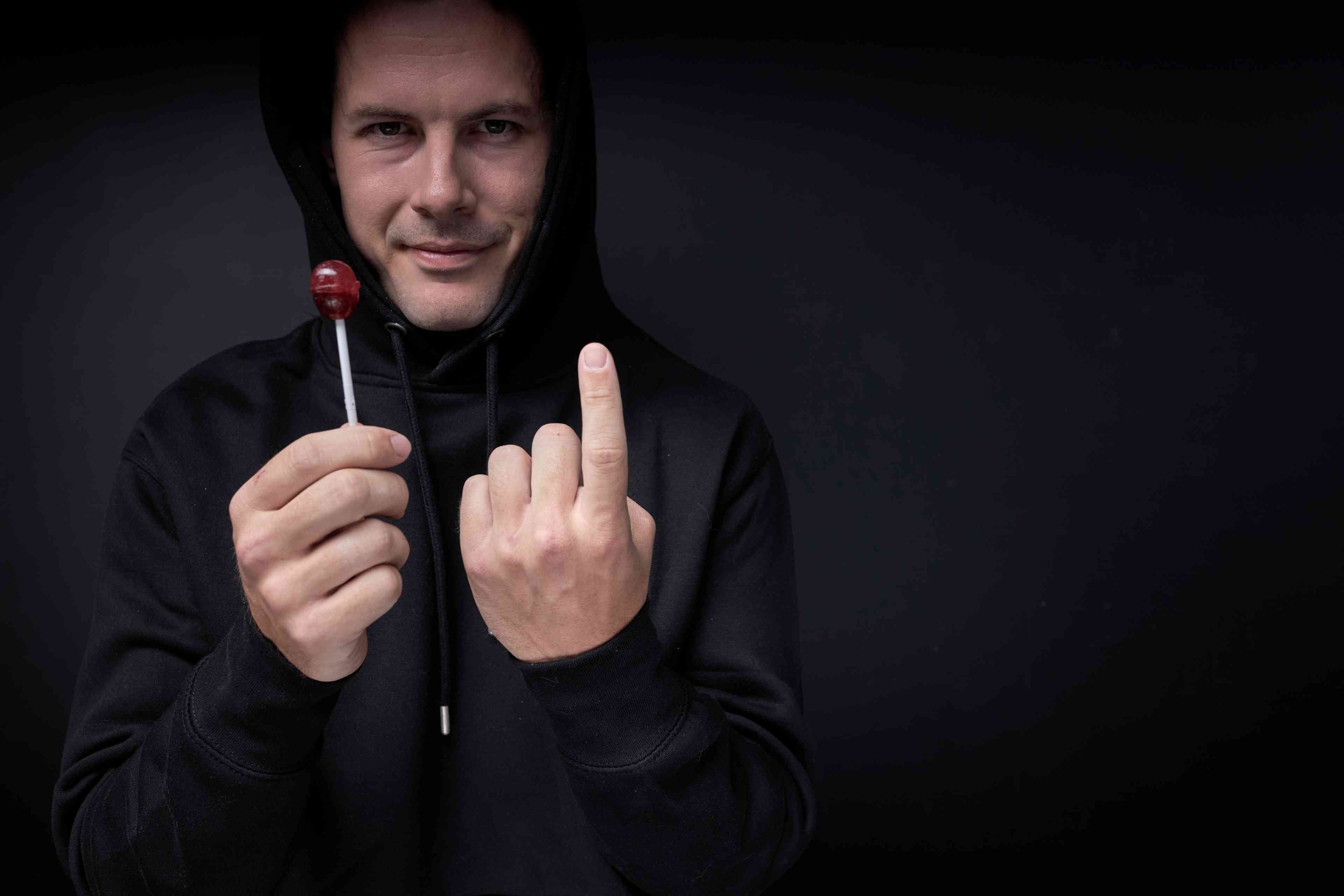 Threatening adult man offering candy lollipop to children background