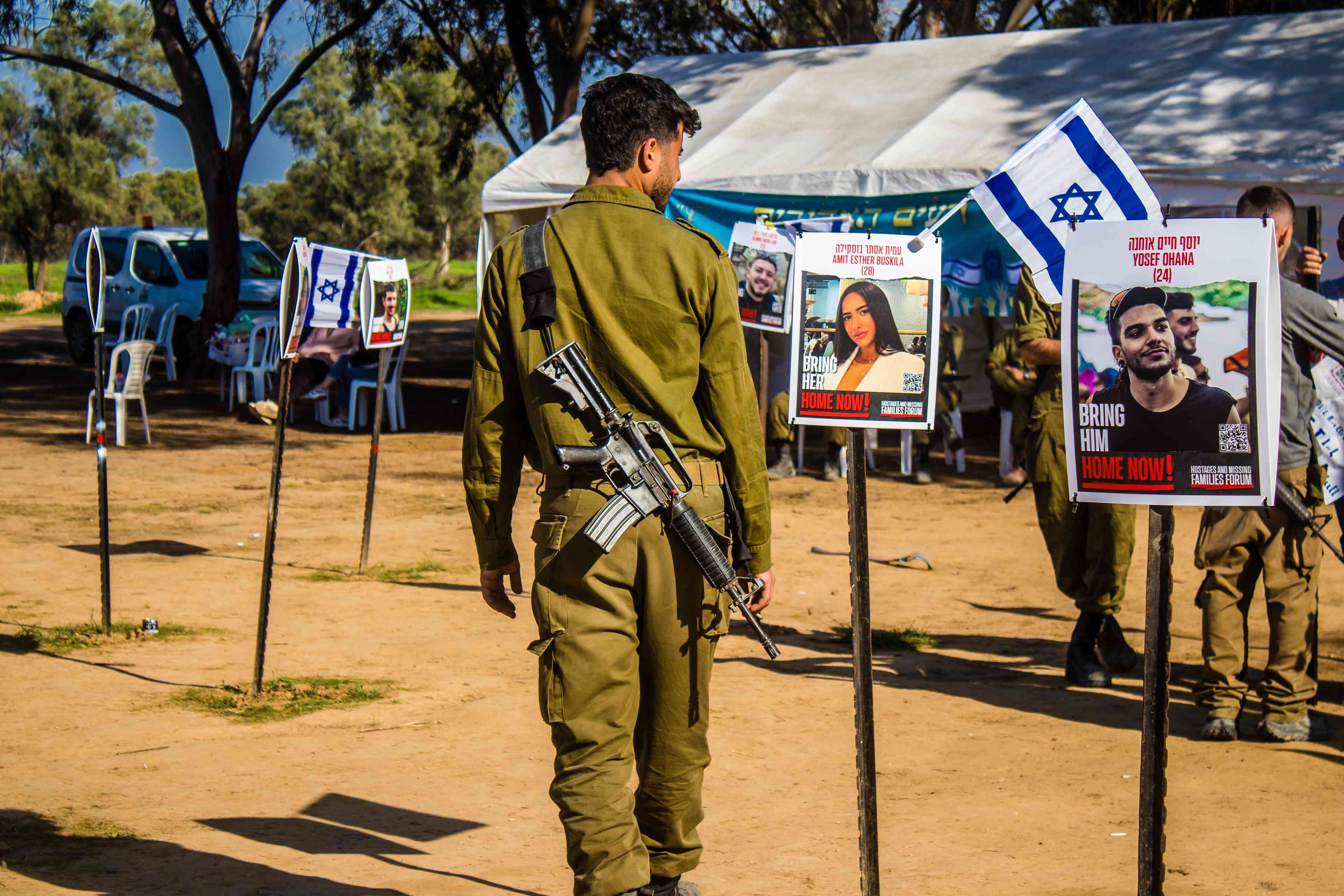 Memorial composed of photos of young Israelis killed during the terrorist attack on the NOVA Festival background