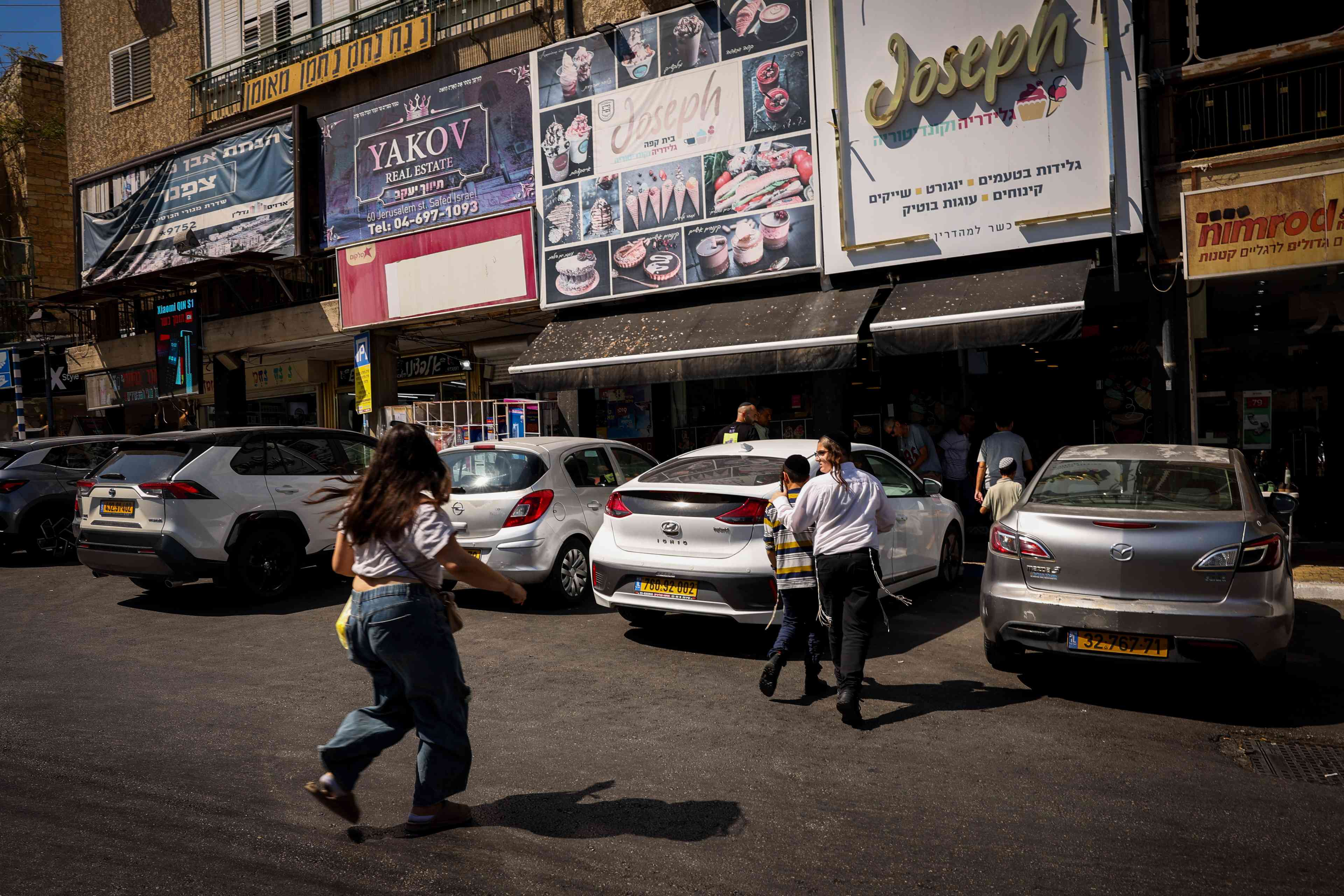 People take cover as a siren warns of incoming missiles fired from Lebanon, in the northern Israel city of Tzfat, September 26, 2024 background