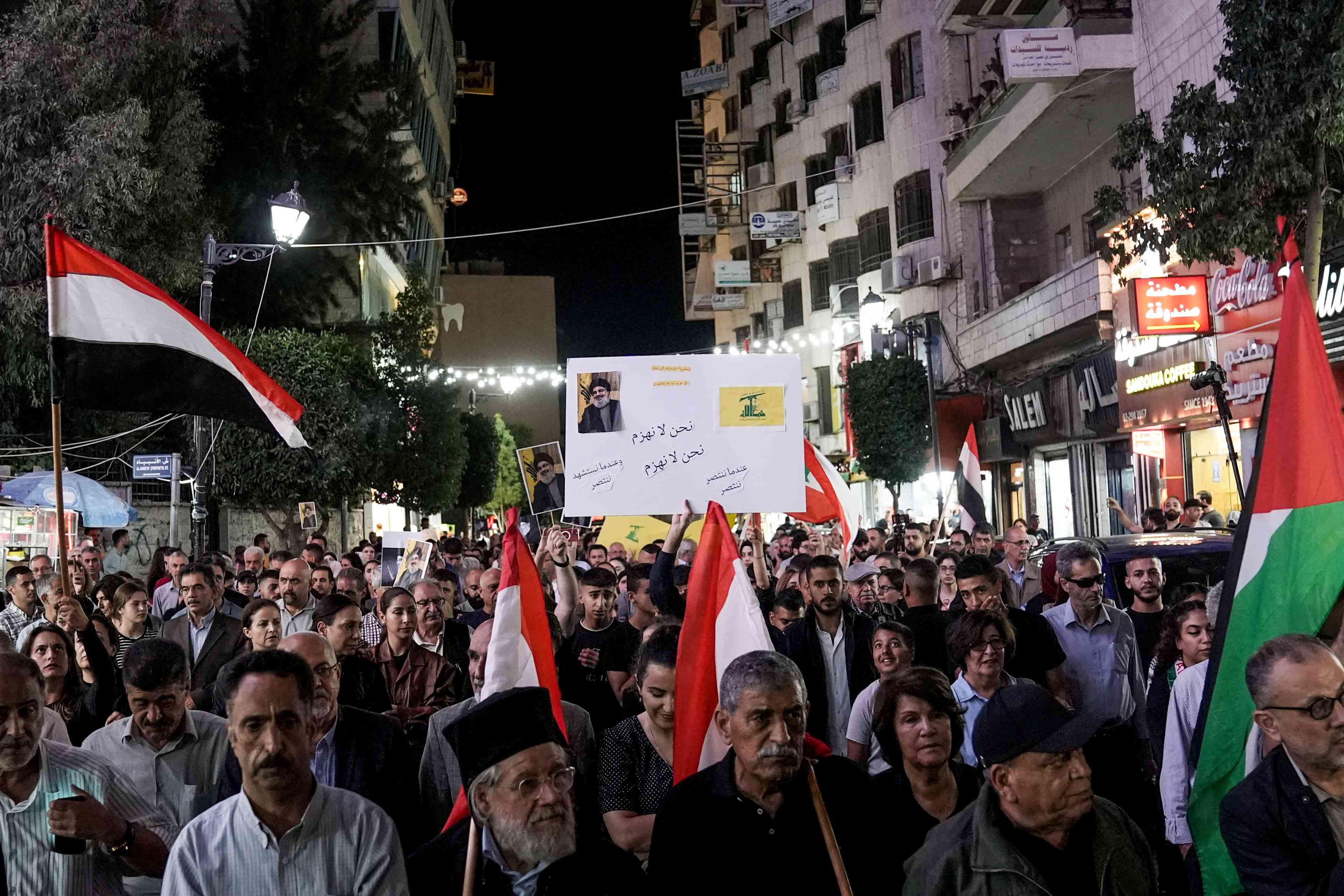 Palestinians hold pictures of Hezbollah Secretary-general Hassan Nasrallah and wave the Lebanese flags during a demonstration against his assassination, Ramallah, September 28, 2024 background