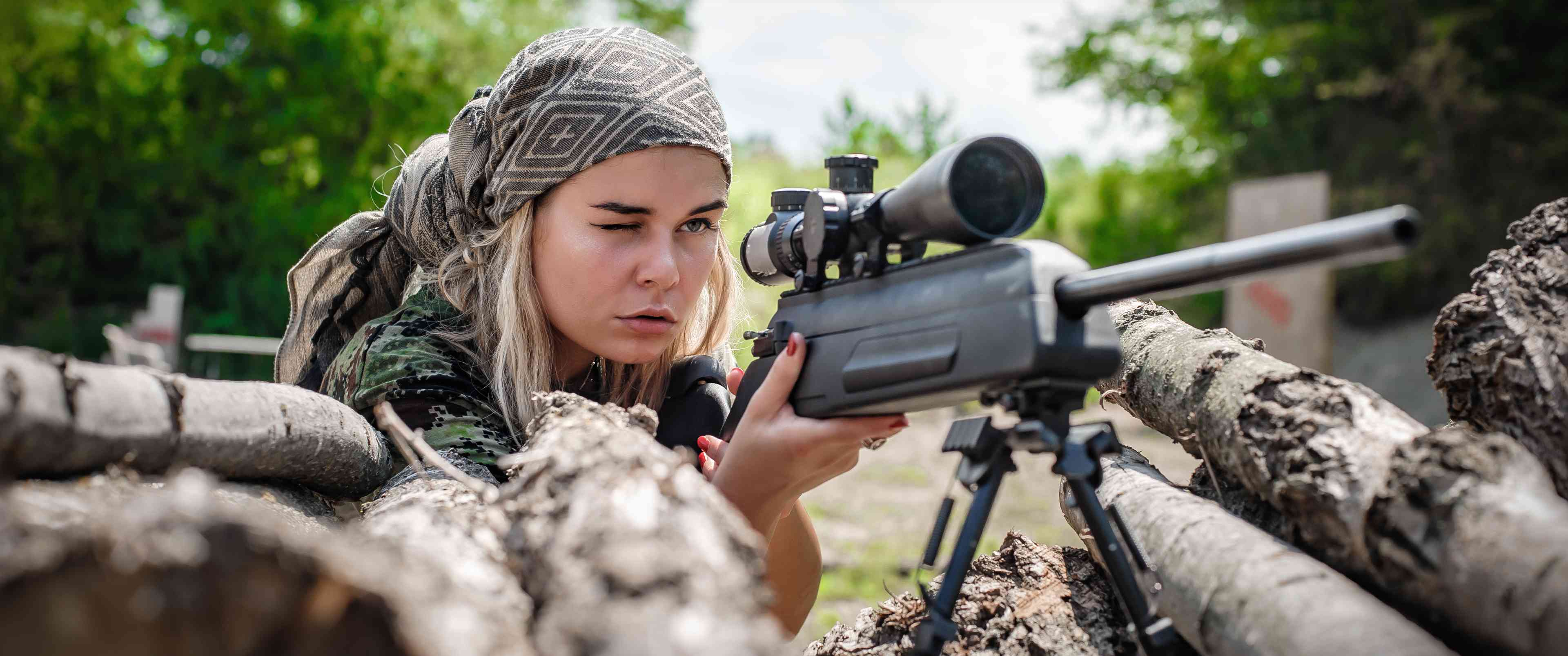 Female soldier shooting with sniper rifle background