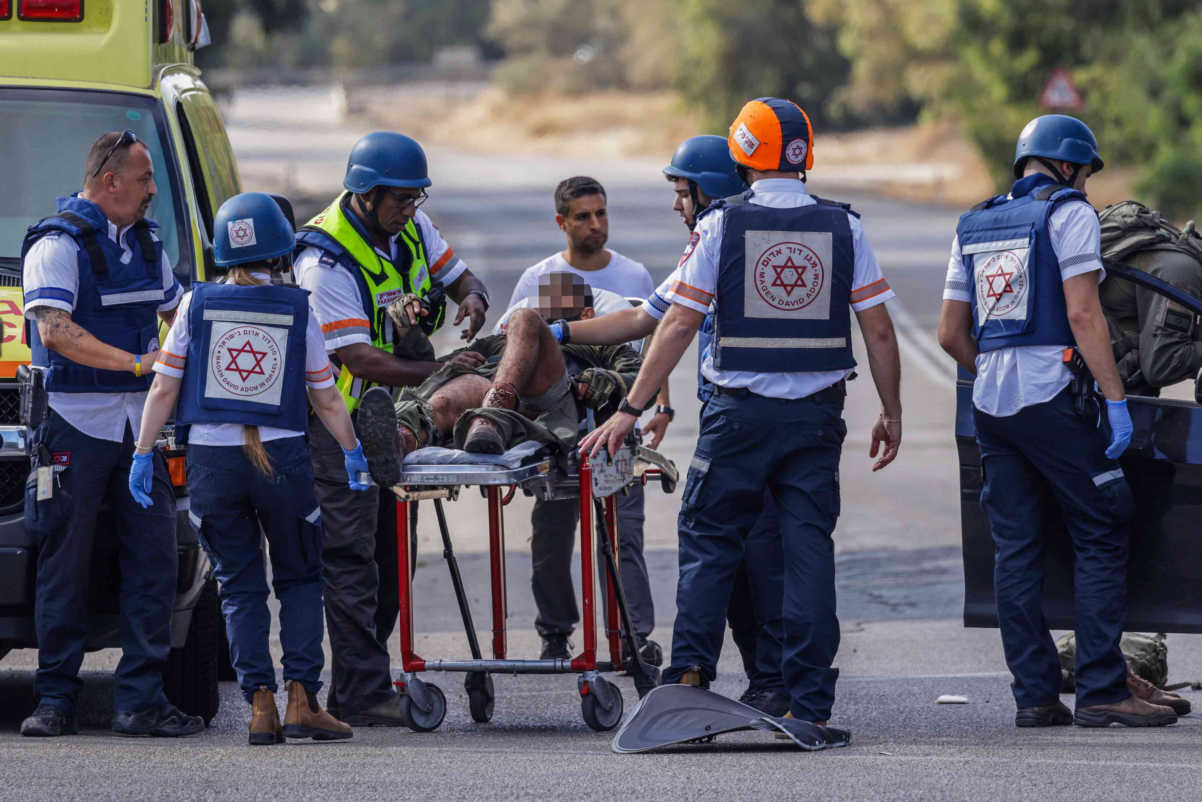 Medics evacuate a wounded Israeli soldier on road 232 near the southern Israeli city of Sderot, October 7, 2023 background