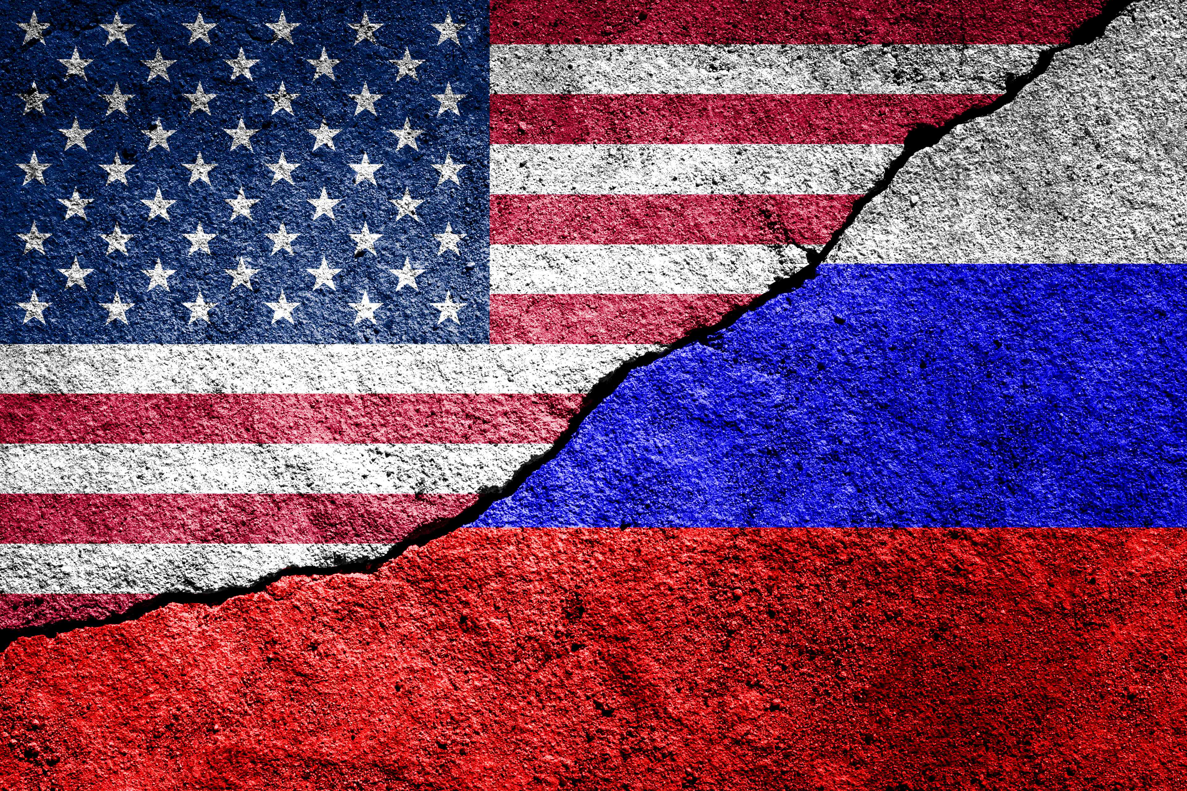 The crack between the Russian and USA flags on the concrete wall background