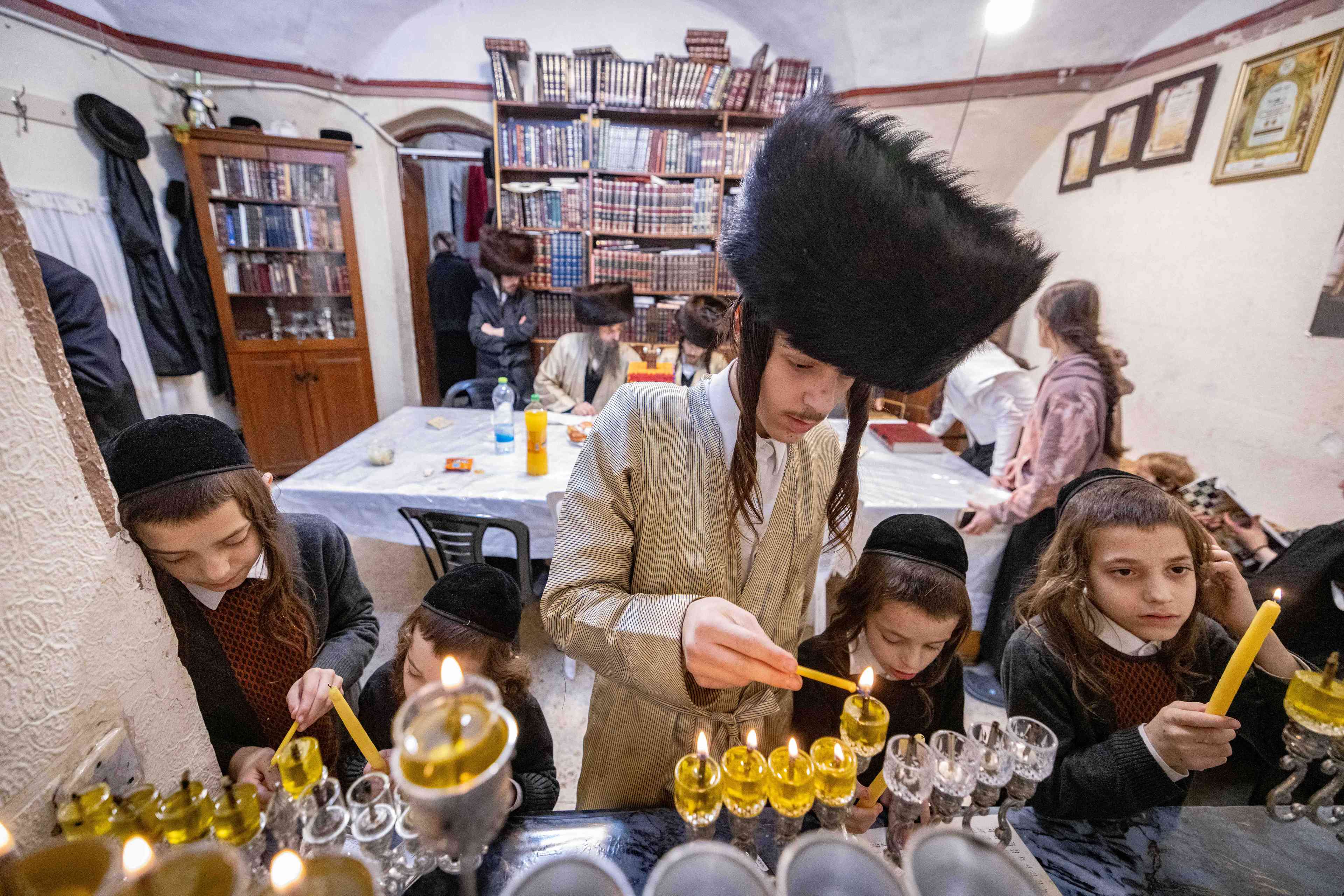 Ultra-Orthodox Jews light candles during the Jewish holiday of Hanukkah, in Jerusalem's Mea Shearim neighbourhood on December 28, 2024 background