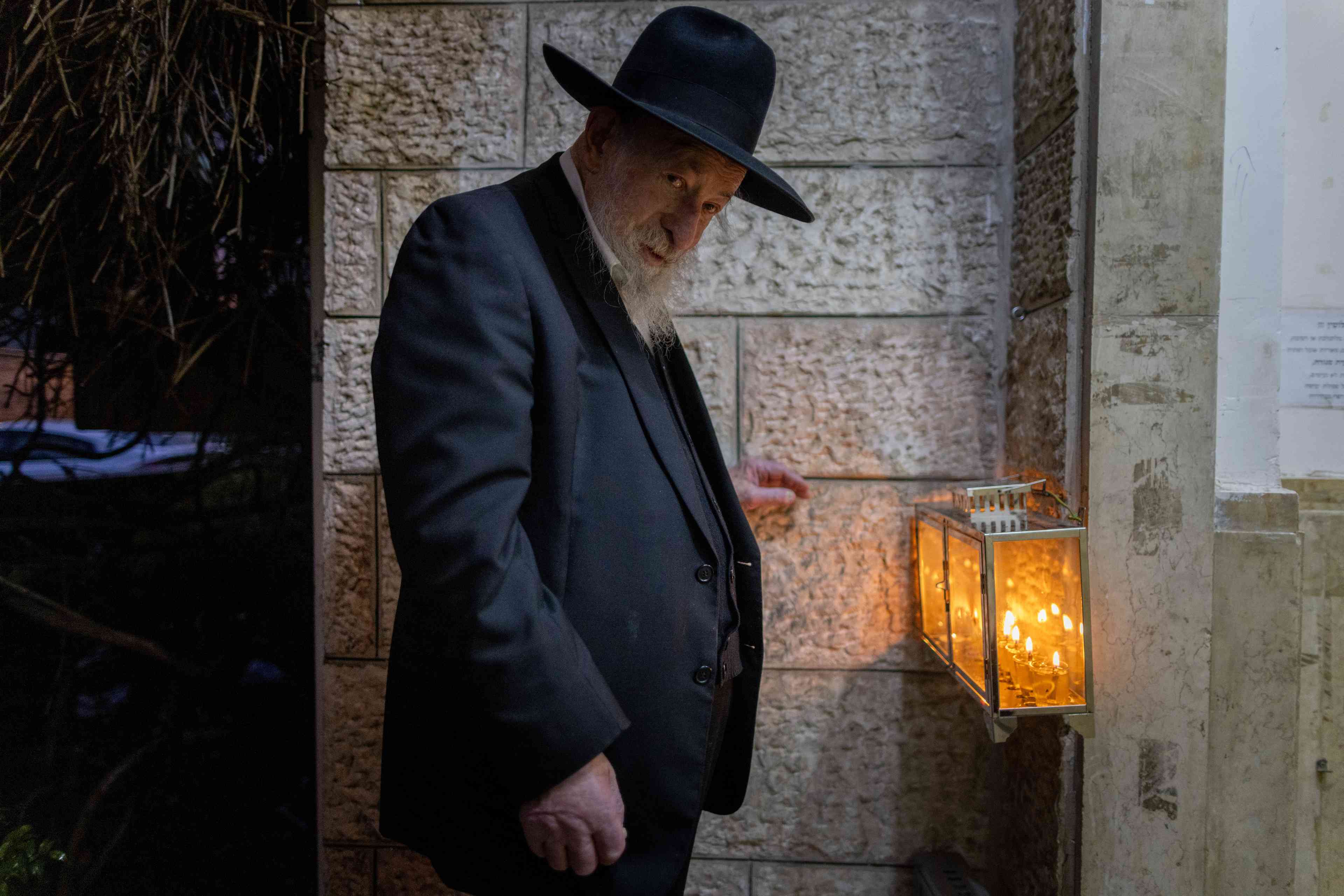 Holocaust survivor Rabbi Shmuel Geffen lights the Hanukkia (menorah) in Jerusalem's Ultra Orthodox Mea Shearim neighborhood, on the sixth night of the Jewish holiday of Hanukkah, December 30 2024 background