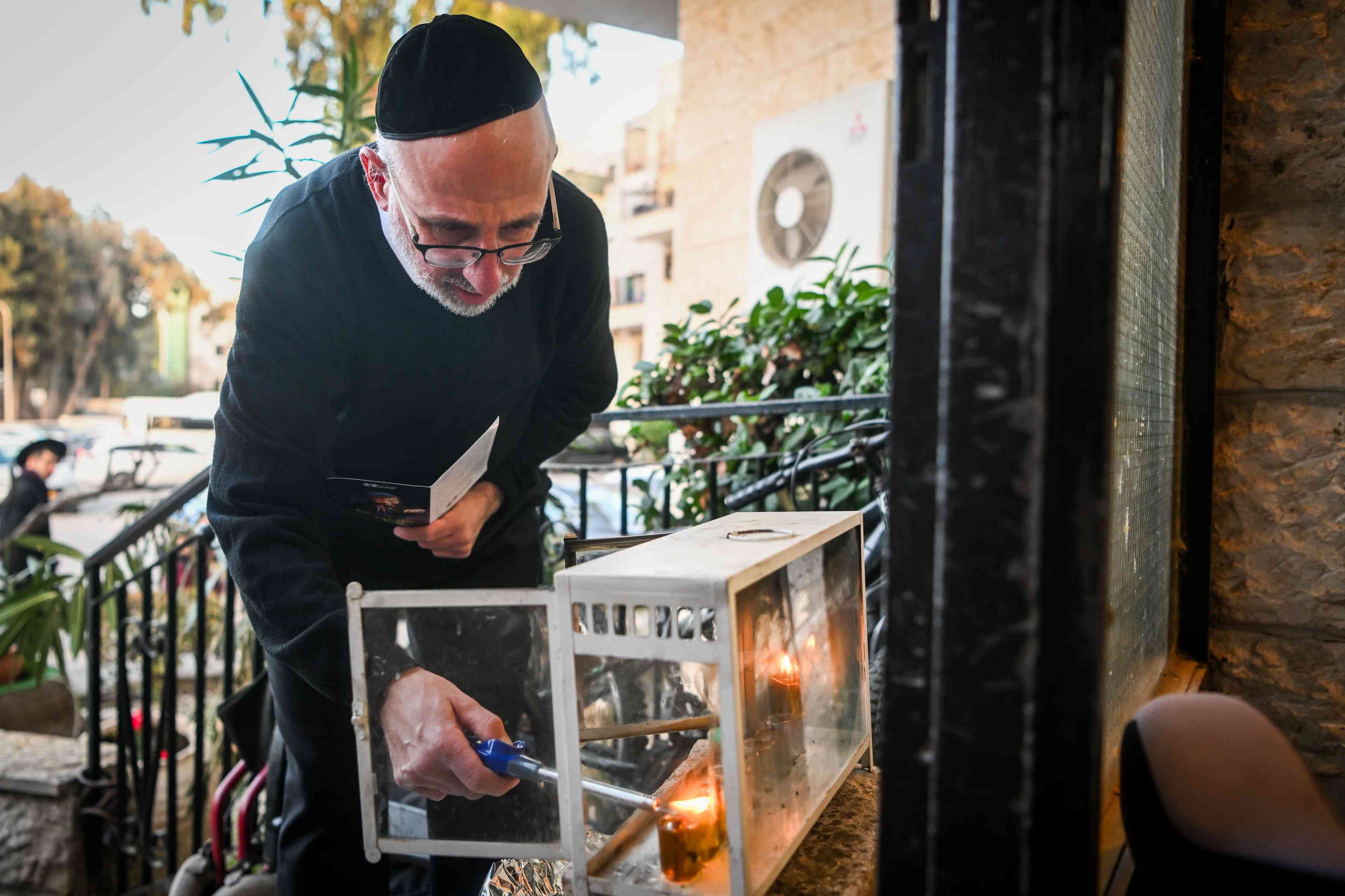 A Jewish family light candles on during the Jewish holiday of Hanukkah, in Jerusalem on December 27, 2024 background
