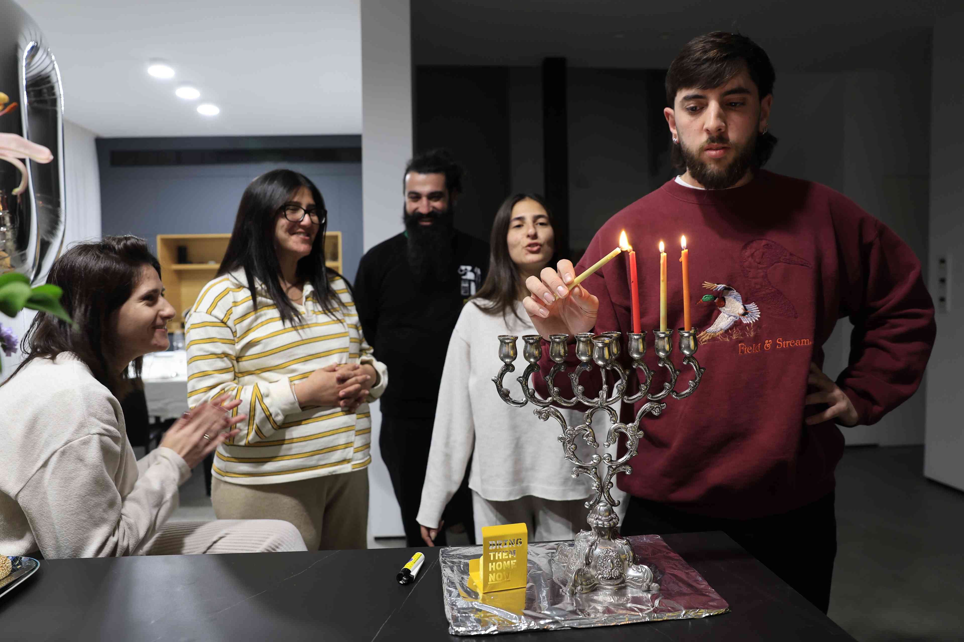 Jews light the Hanukkah candles with a candle for Israelis held hostage in Gaza, during the Jewish holiday of Hanukkah, in Mishmar David, on December 27, 2024 background