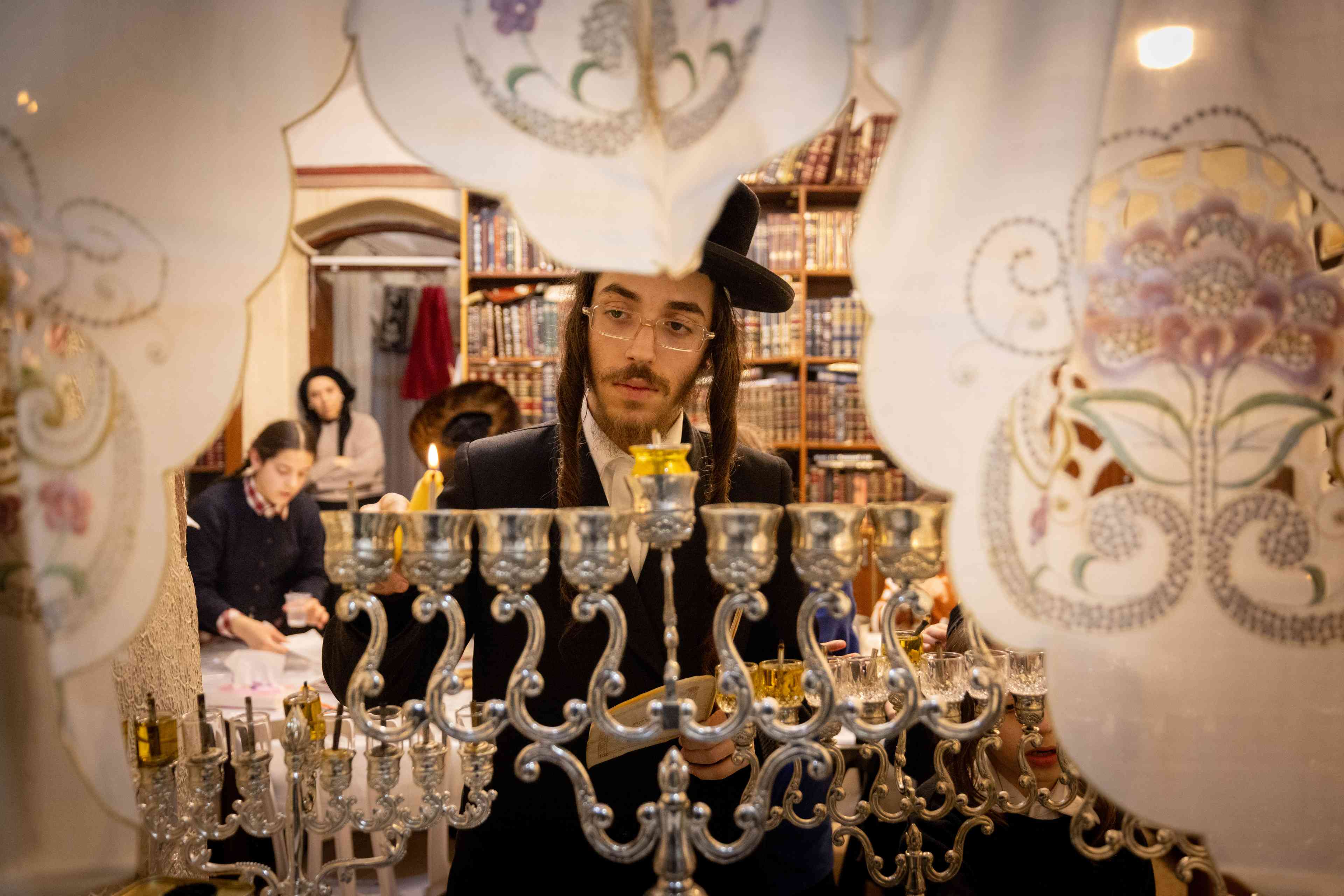 Ultra-Orthodox Jews light candles on the second night of the Jewish holiday of Hanukkah, in Jerusalem's Mea Shearim neighbourhood on December 26, 2024.  background