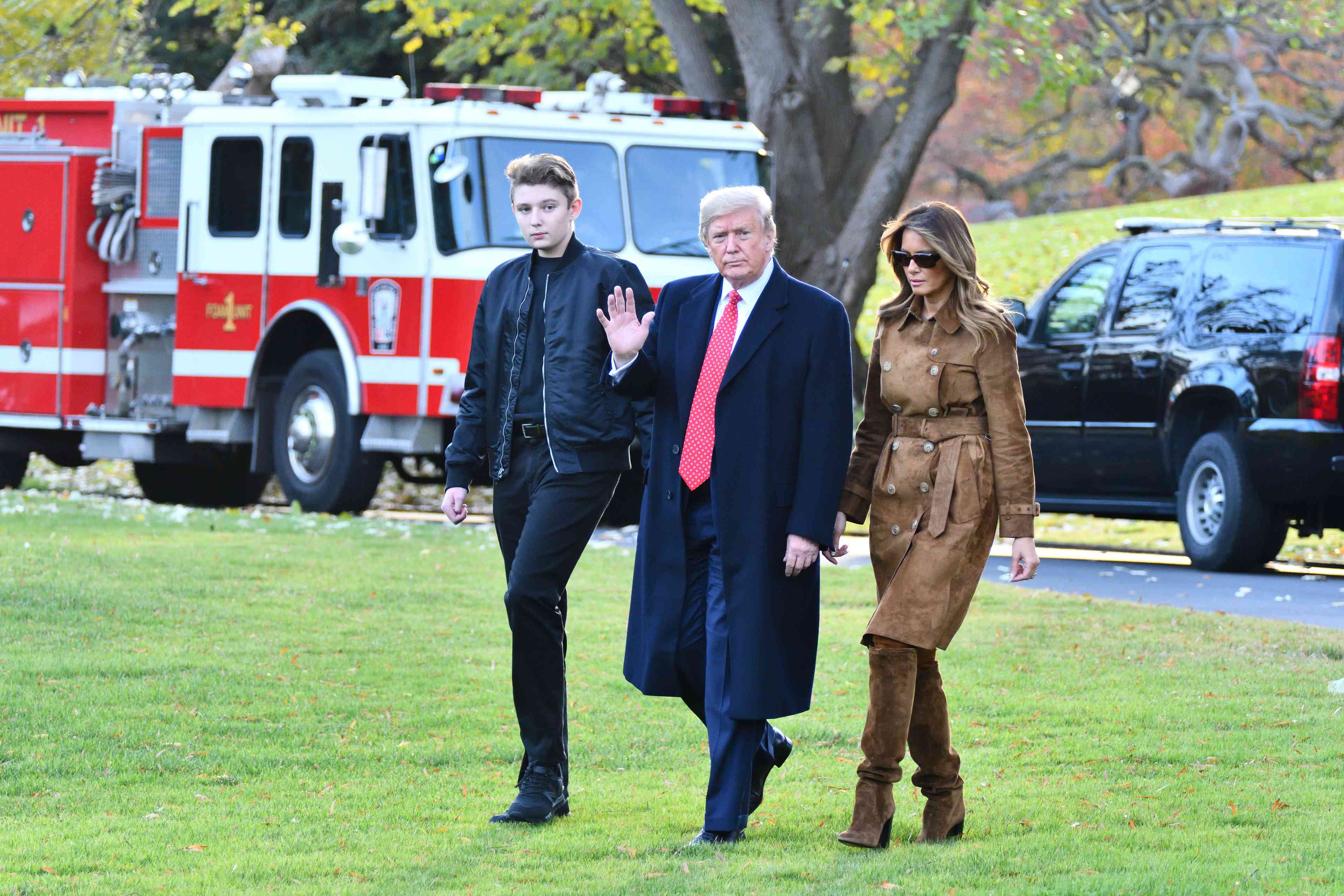 President Donald Trump waves as he walks with First Lady Melania Trump and their son Barron, 2019 background