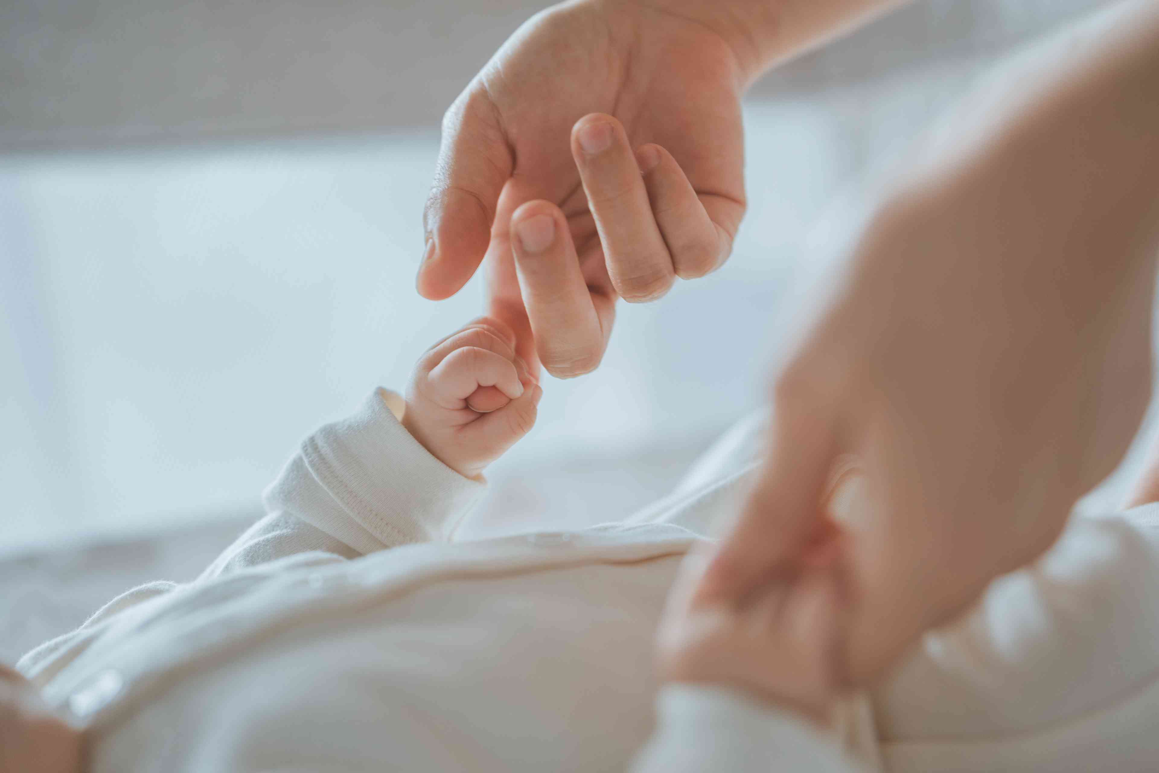 Close-up little hand of baby holding hand of mother background