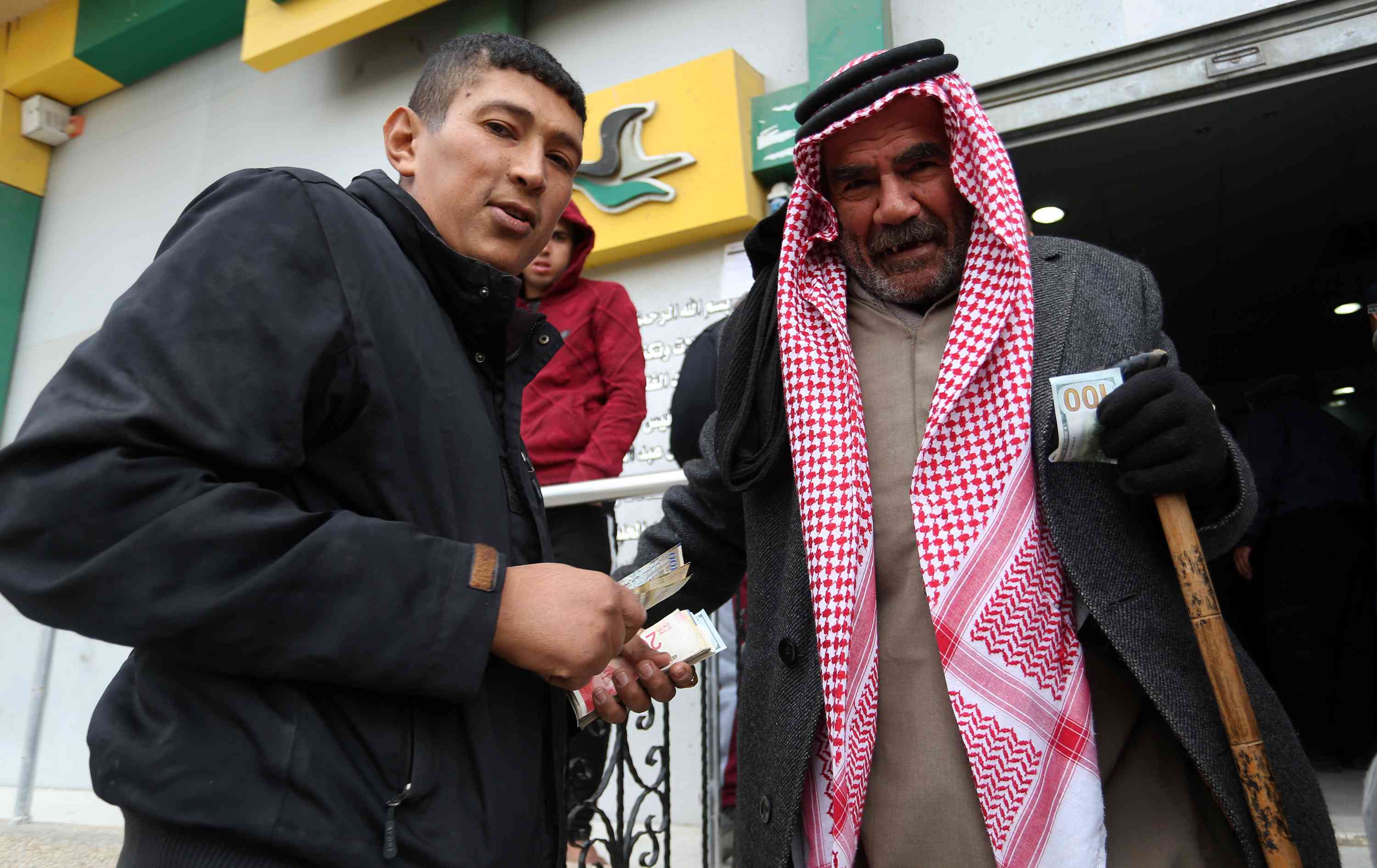 Palestinians receive their financial aid as part of an aid allocated by Qatar, at a post office in Rafah, in the southern Gaza Strip