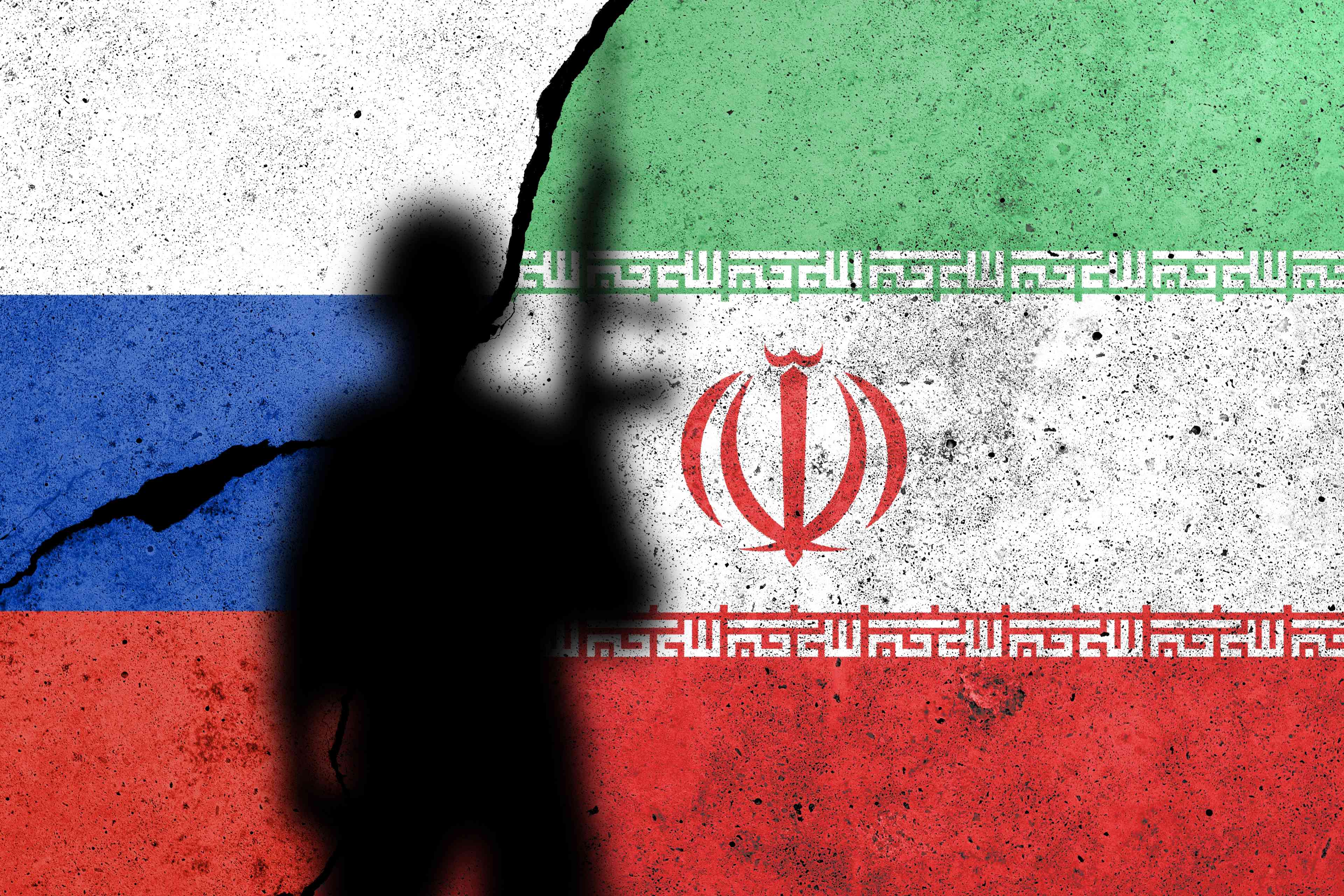 Flags of Russia and Iran painted on the concrete wall with soldier shadow. See less background