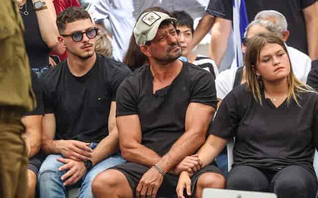 Oren Smadga (center) attends the funeral of his son, Omer Smadga, who was killed fighting in Gaza background