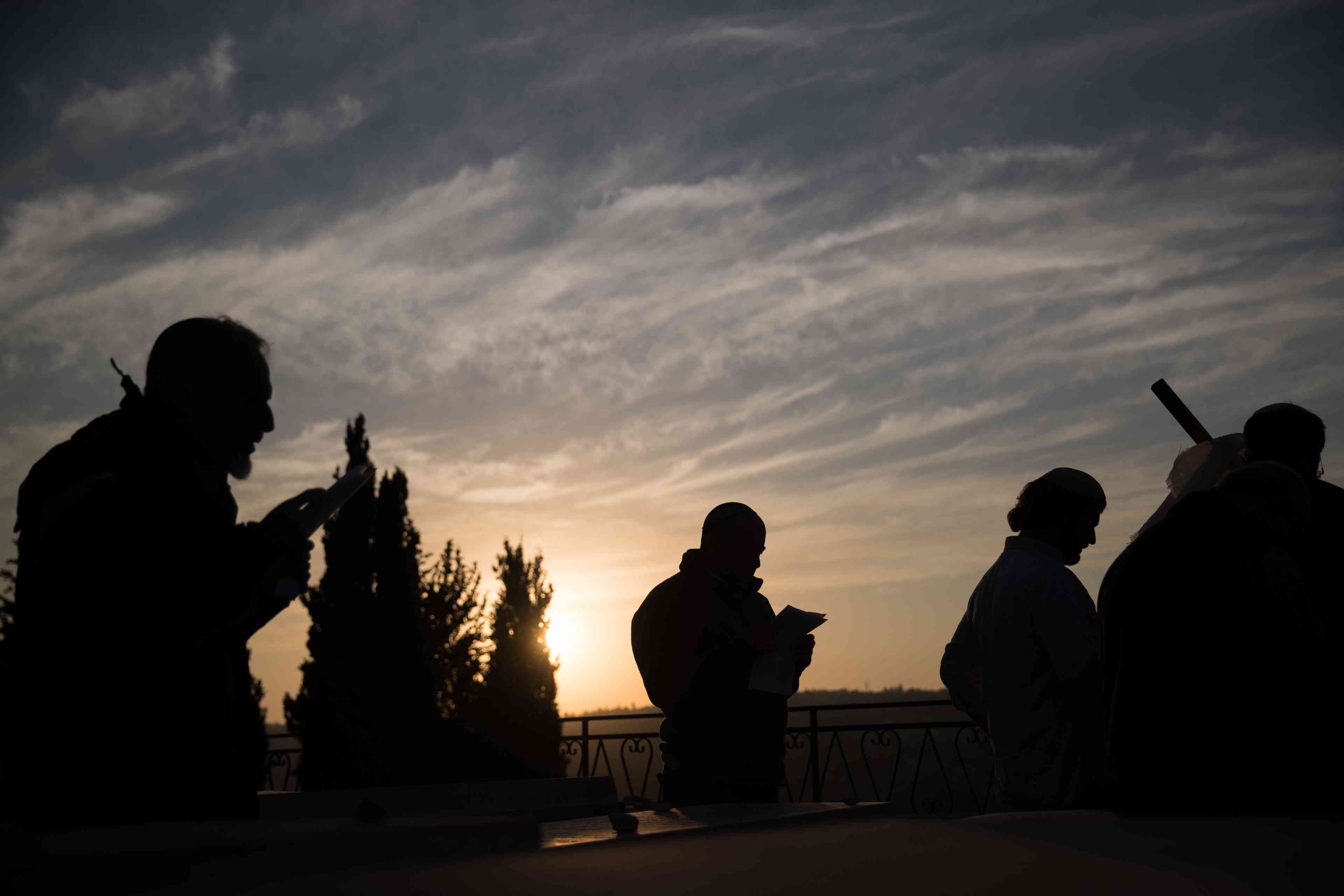 Followers of the late Rabbi Meir Kahane, founder of both the Jewish Defense League (JDL) and "Kach" an Israeli political party, pray at his grave at the Givat Shaul cemetery background