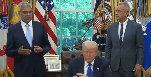 Donald Trump, flanked by Robert Kennedy, Jr. and Jay Bhattacharya. background