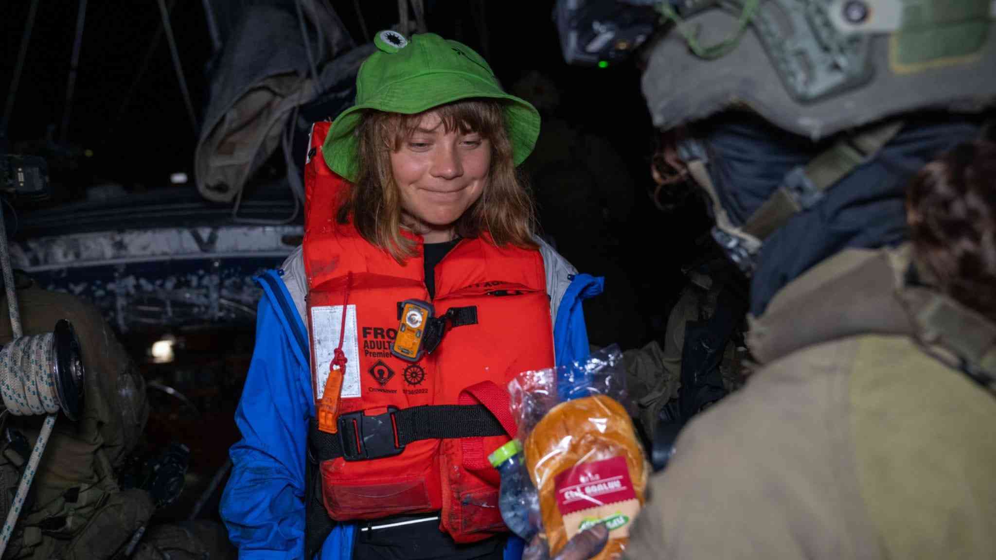 Greta being offered a sandwich on the flotilla. background