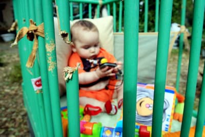 An Israeli baby is playing in his damaged bed at Kibbutz Mefalsim caused by rocket fired from the Gaza Strip 