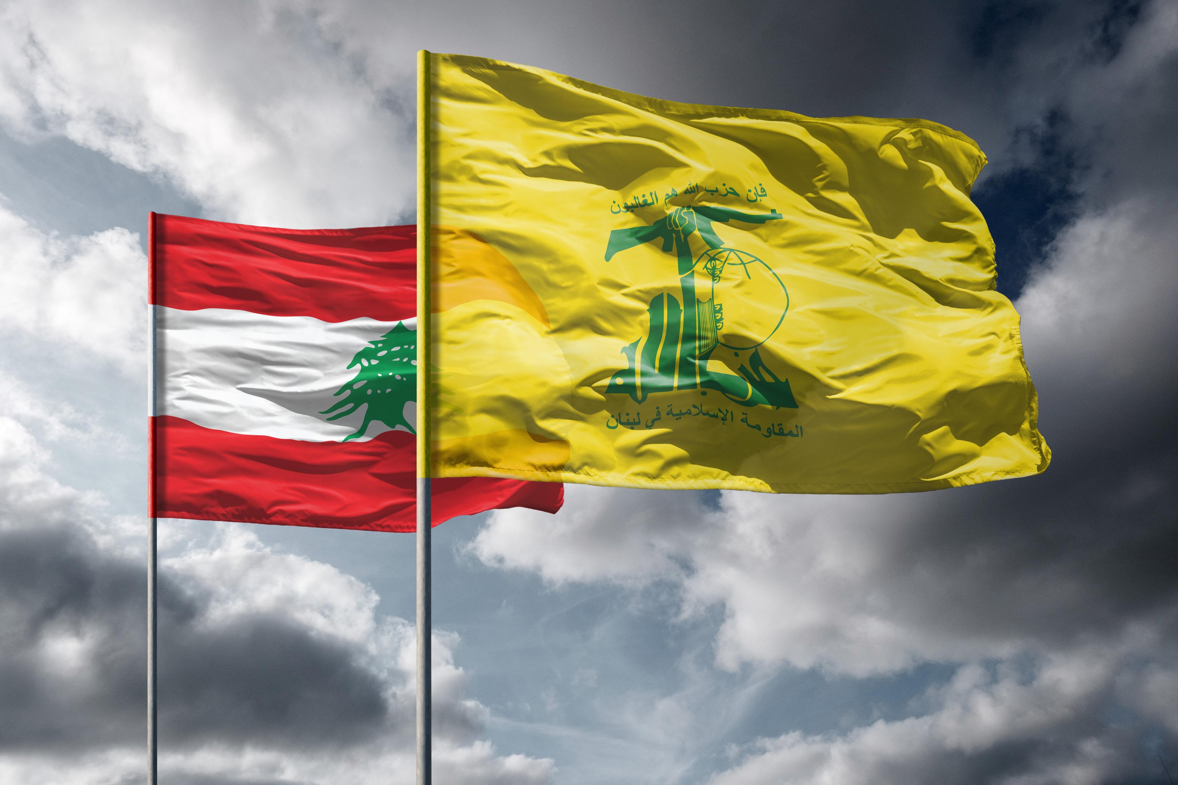 Flags of Lebanon and Hezbollah above dark sky Flags of Lebanon and Hezbollah above dark sky