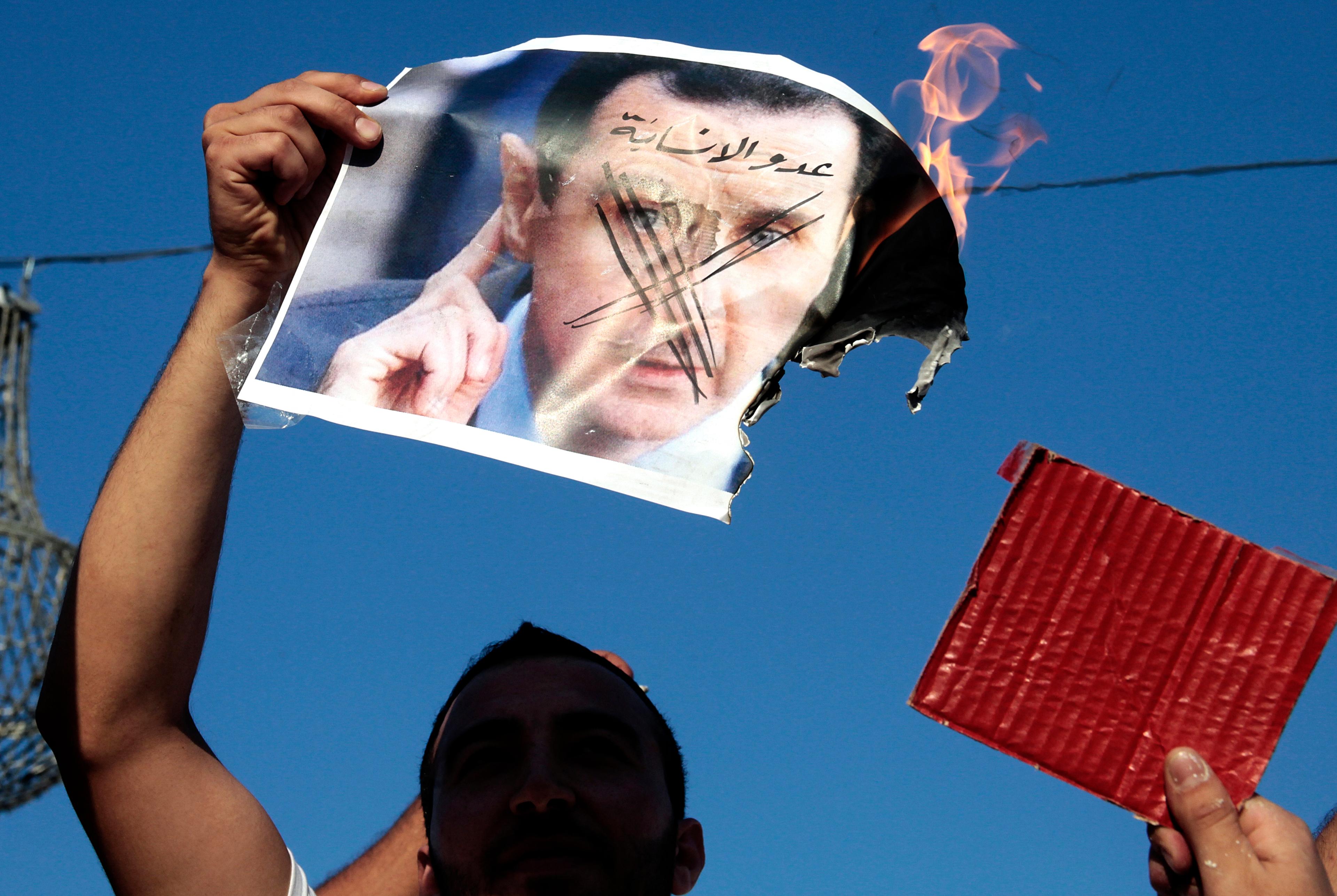 Protestors burning Assad's image. Protestors burning Assad's image.