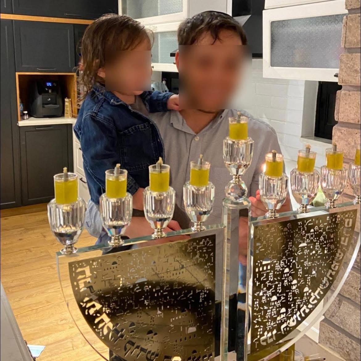 Military reservist lighting Hannukah candles with his child Military reservist lighting Hannukah candles with his child