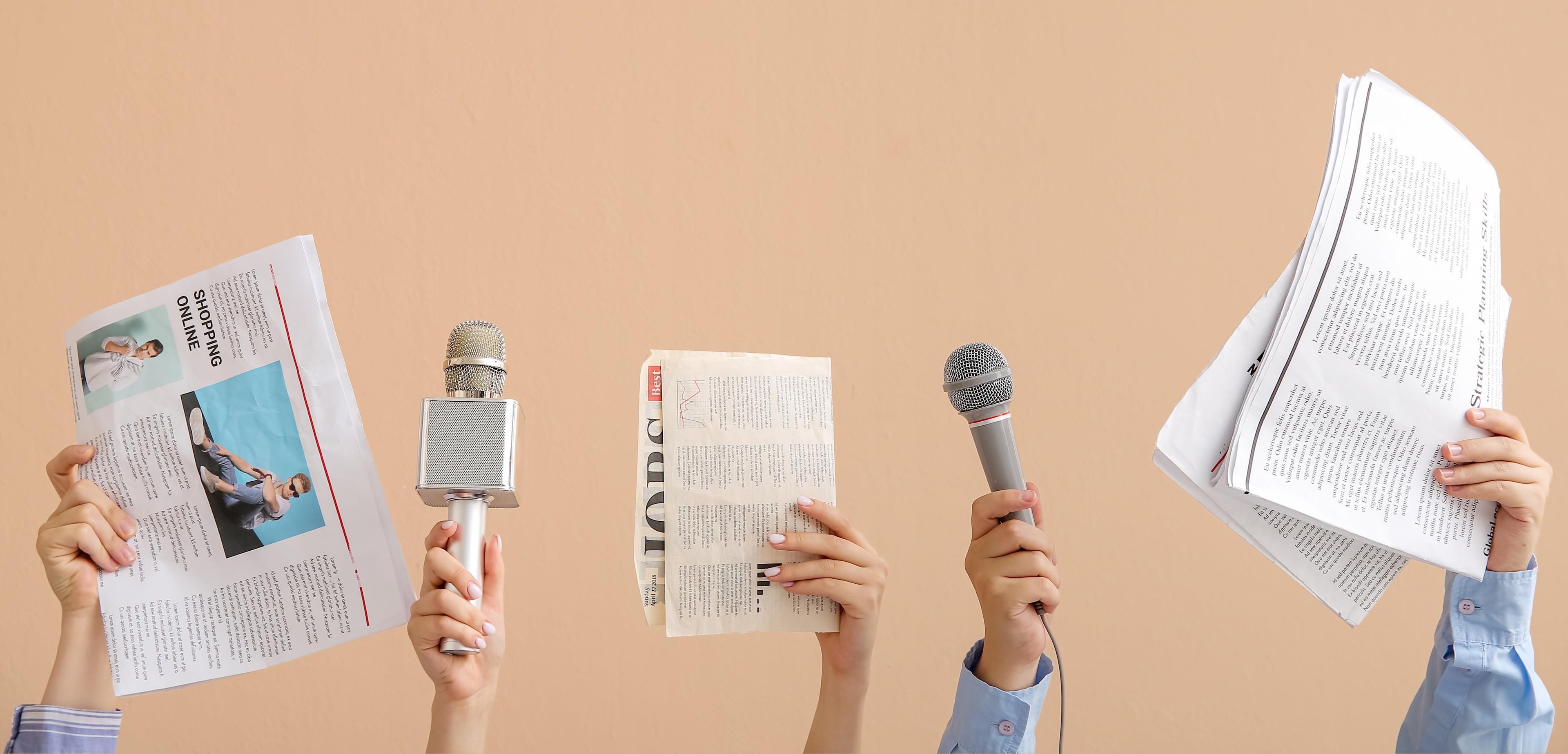Female hands with microphones and newspapers on beige background 
