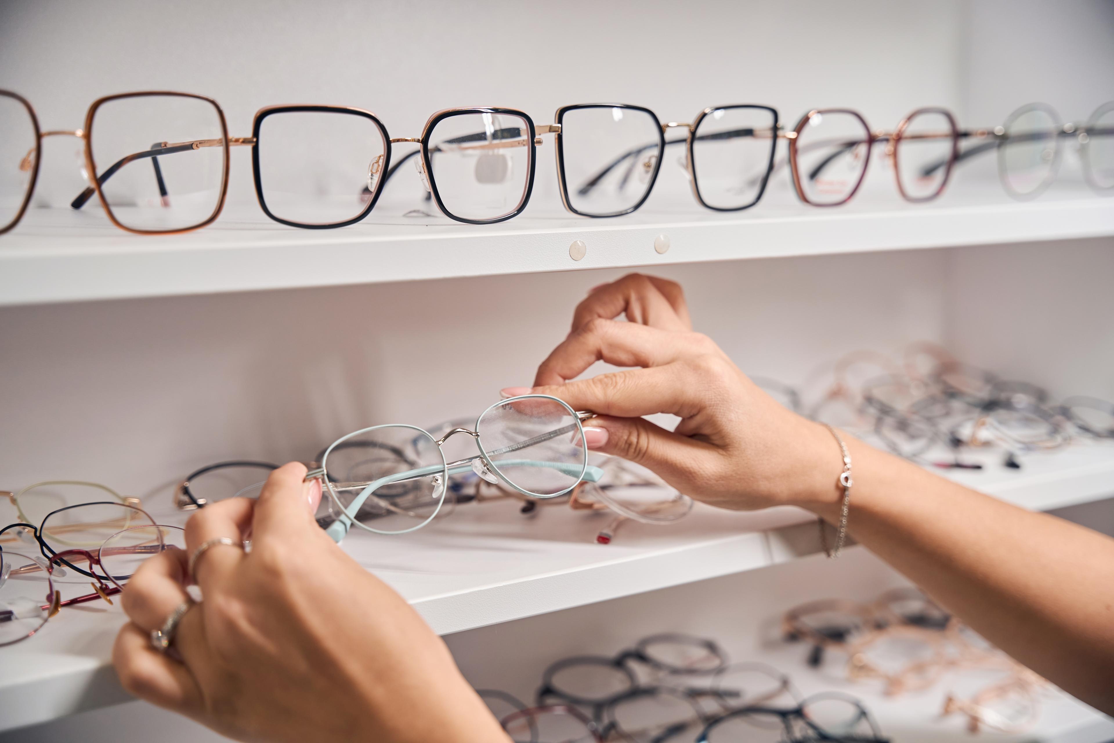 Hands selecting glasses from a display shelf 
