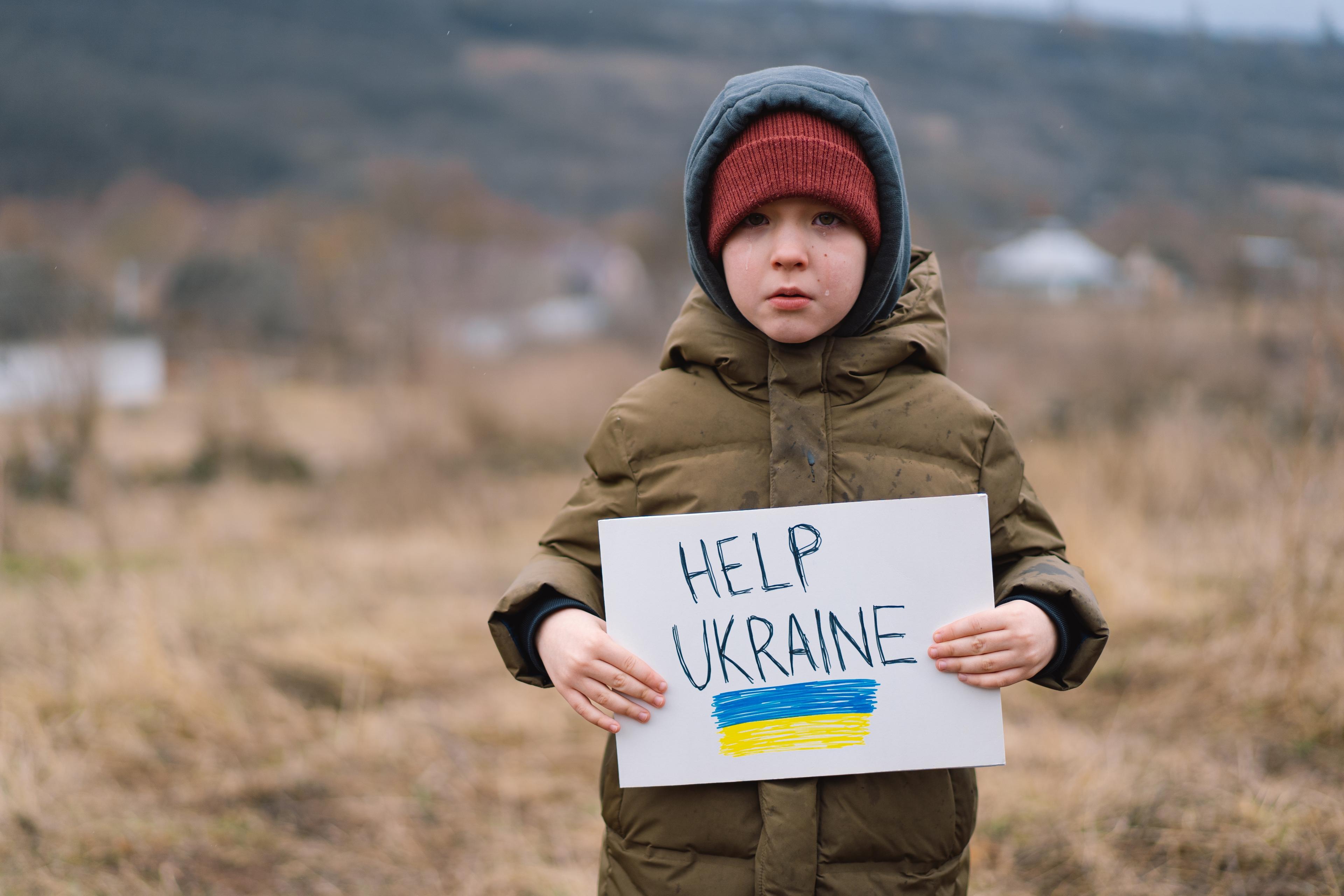 Ukrainian boy holding sign asking for help