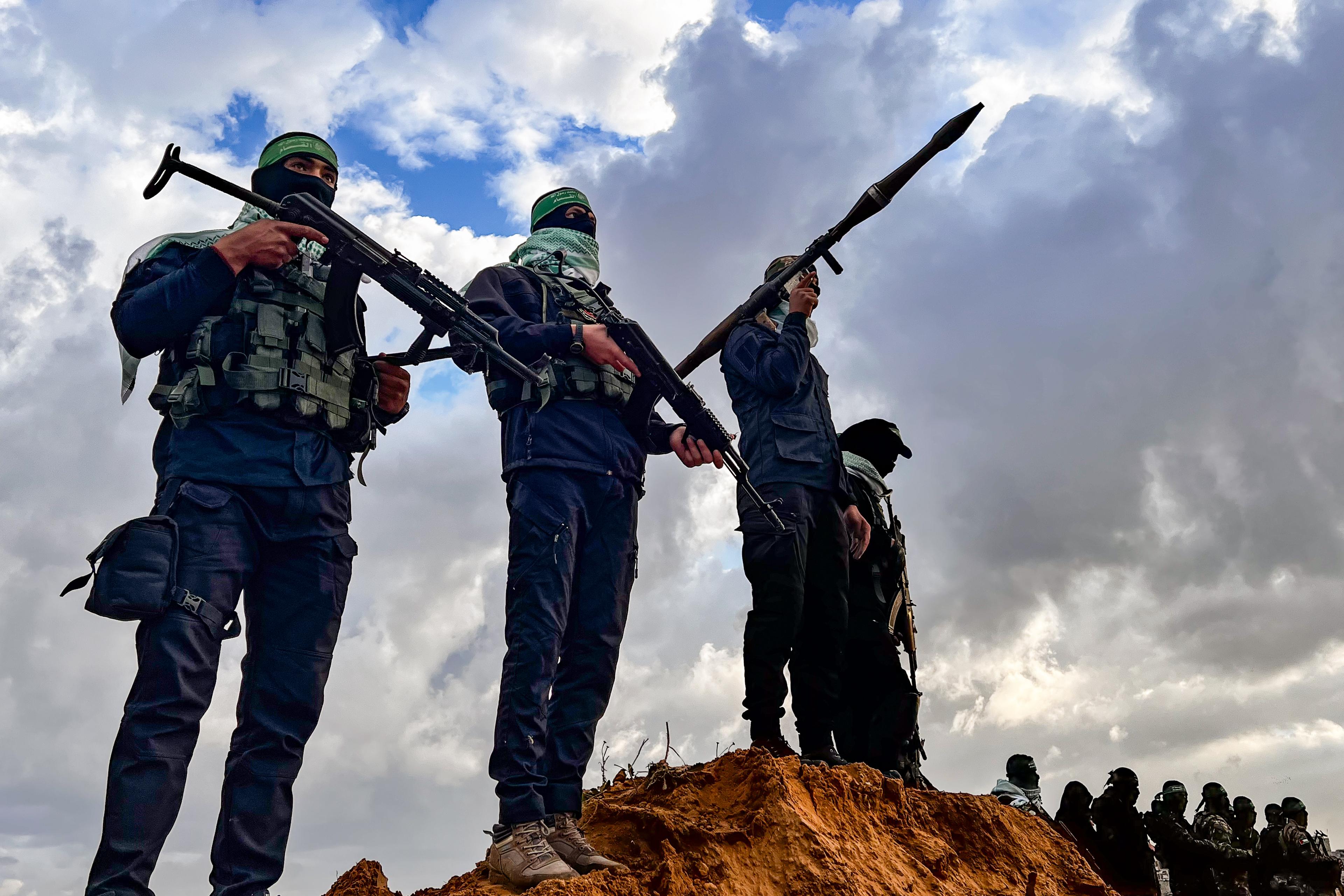 Members of the Al-Qassam Brigades guard while Palestinians waiting for the hand over of the bodies of four late Israeli hostages to the Red Cross, as part of the ceasefire agreement between Israel and Hamas, in Khan Yunis, February 20, 2025.