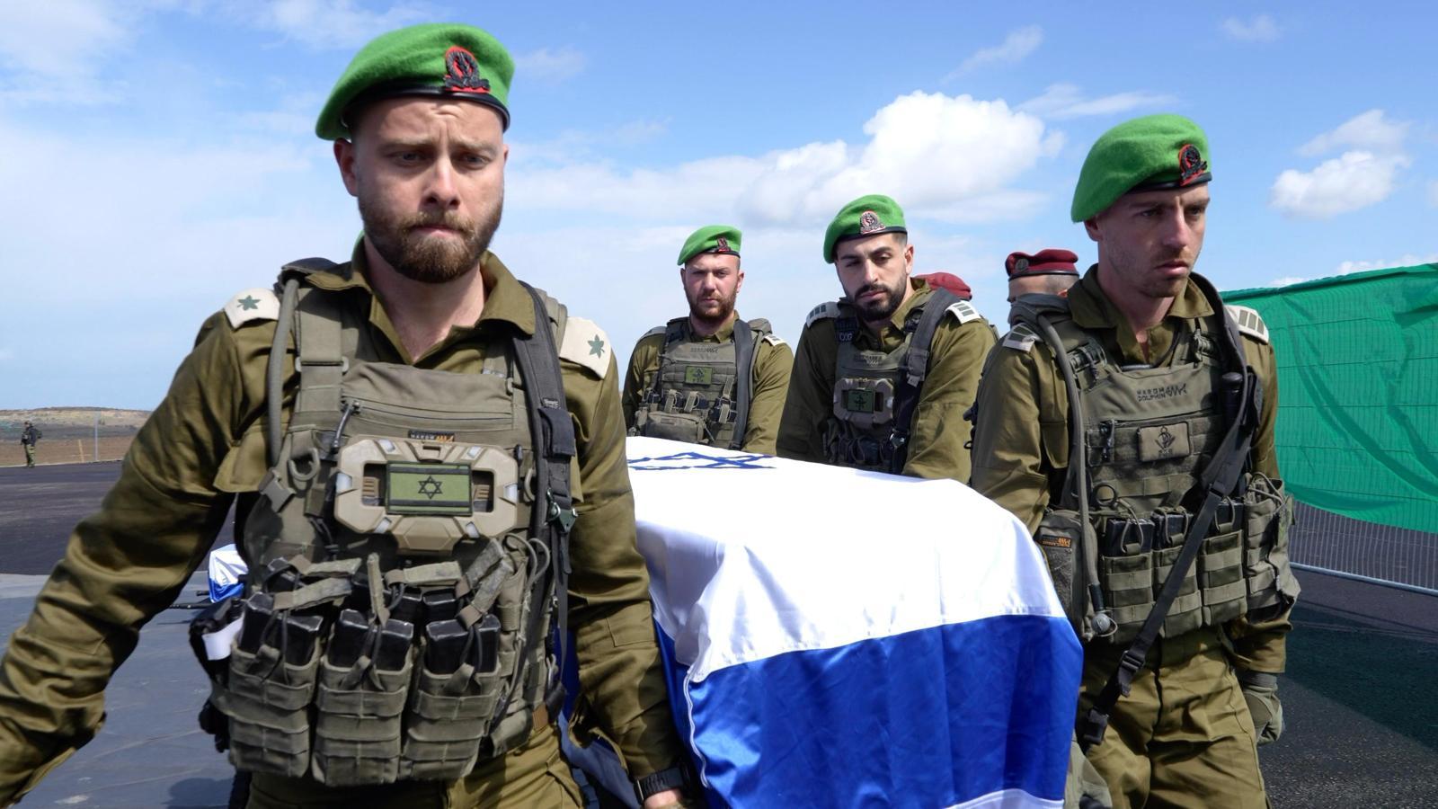 IDF soldiers carrying one of the slain hostages, draped in an Israeli flag.