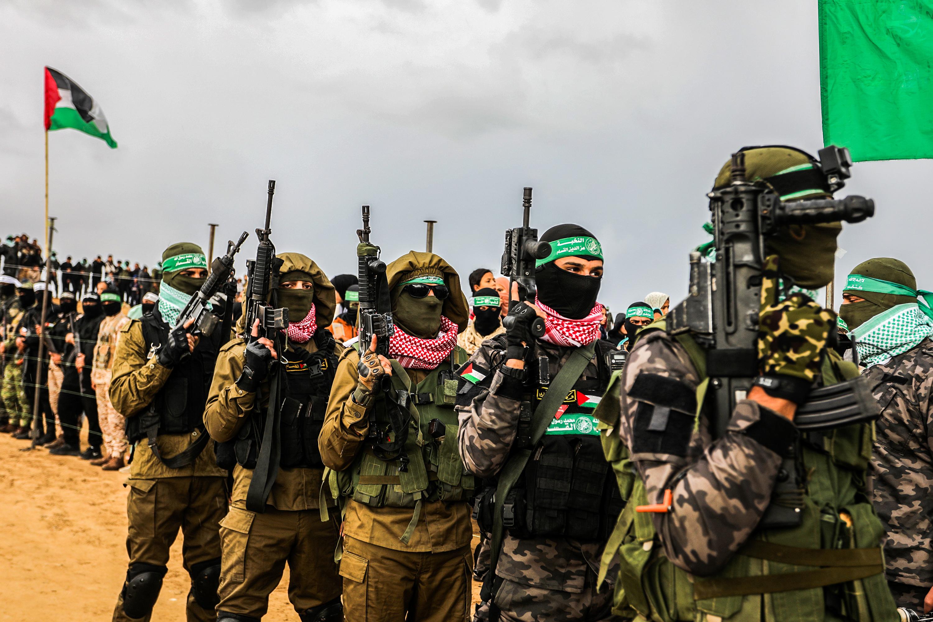 Members of the Al-Qassam Brigades and Palestinians waiting for the hand over of the bodies of four late Israeli hostages to the Red Cross, as part of the ceasefire agreement between Israel and Hamas, in Khan Yunis, February 20, 2025