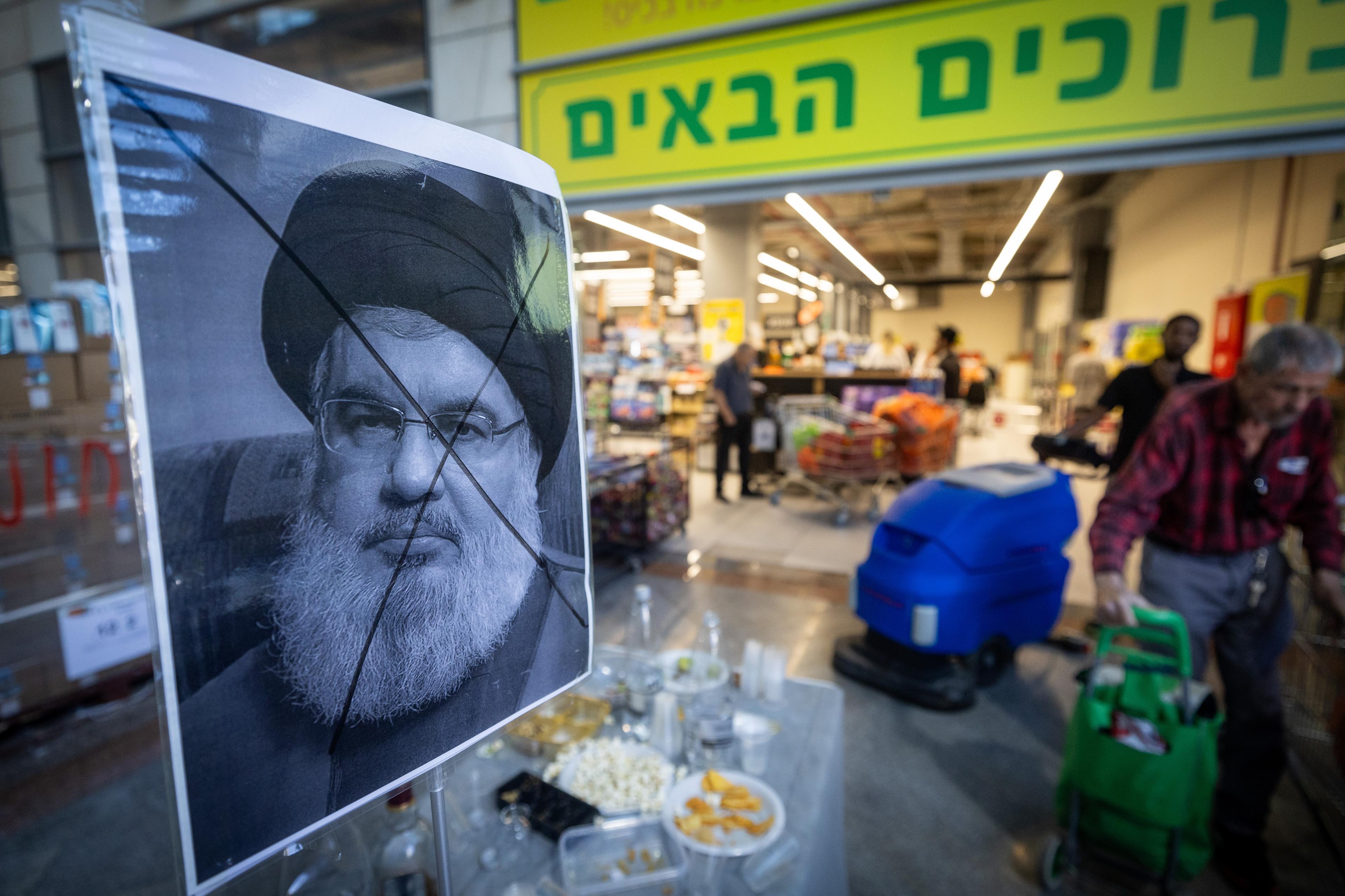A portrait of Hezbollah leader Hassan Nasrallah with an X sign on his face is placed on a table with drinks and food to celebrate his assassination by Israel, outside a supermarket in Jerusalem, September 29, 2024
