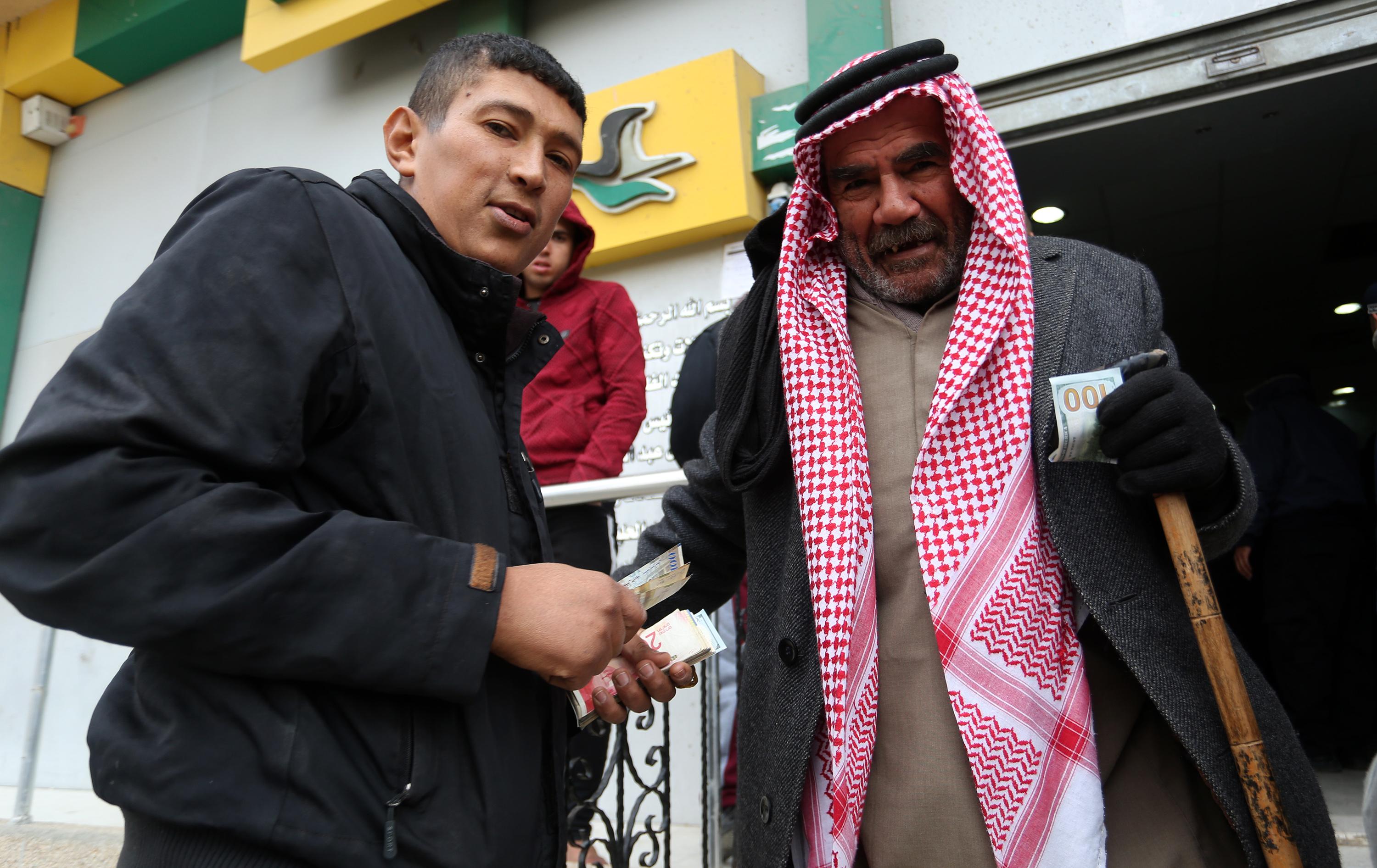 Palestinians receive their financial aid as part of an aid allocated by Qatar, at a post office in Rafah, in the southern Gaza Strip