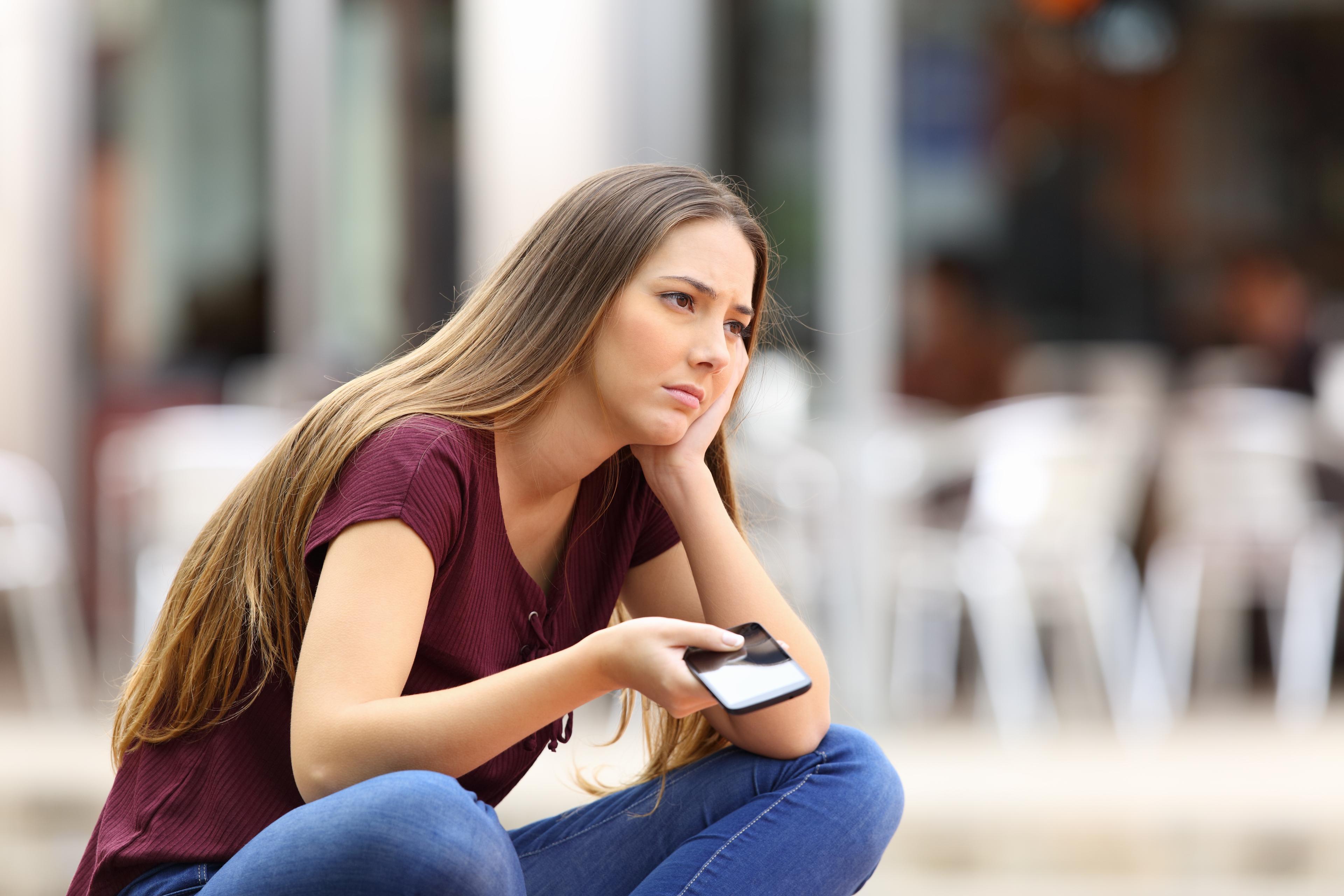 Sad girl waiting for a mobile phone call 