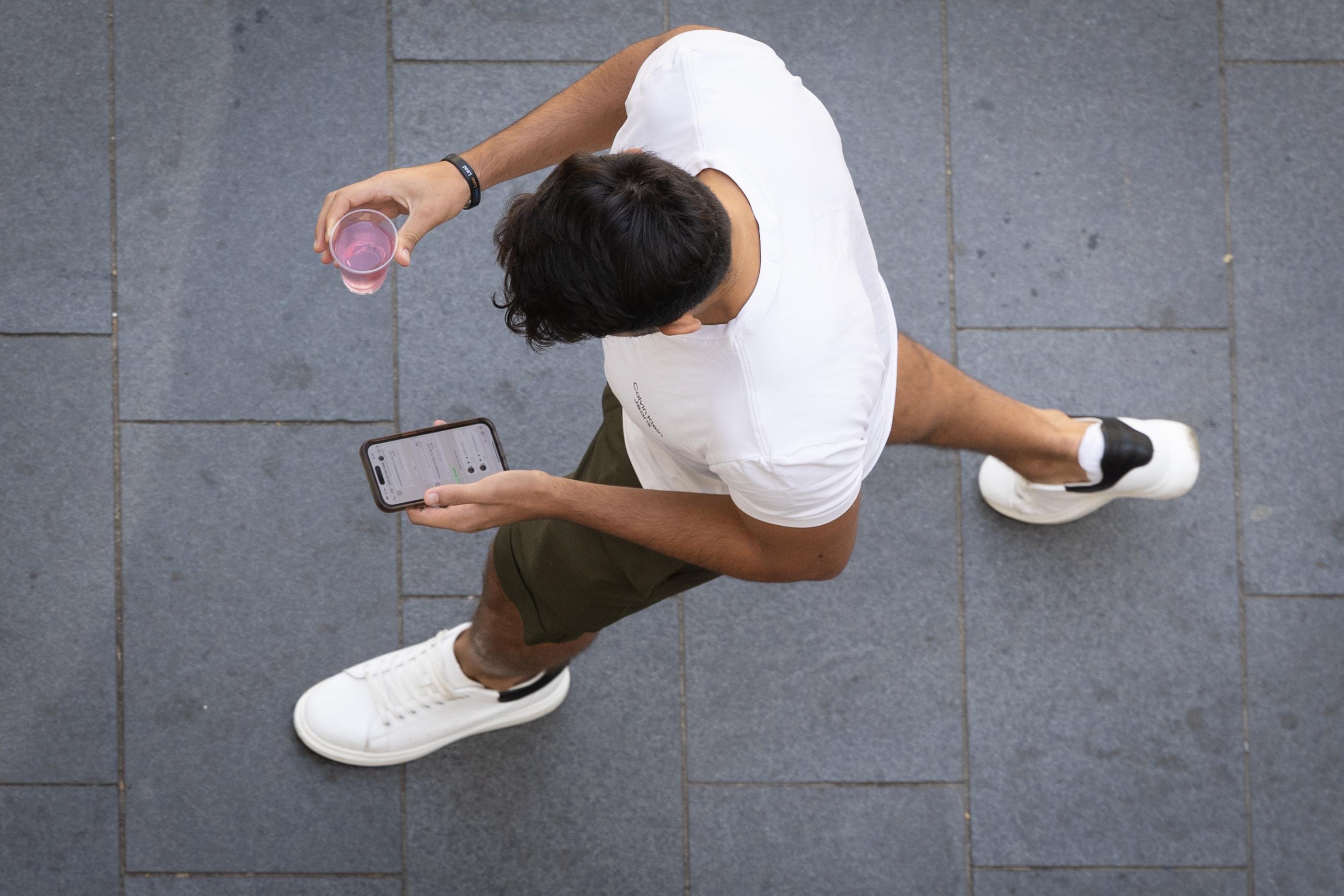 A young man looks on his cellphone while walking on the street in Jerusalem. August 12, 2024. 