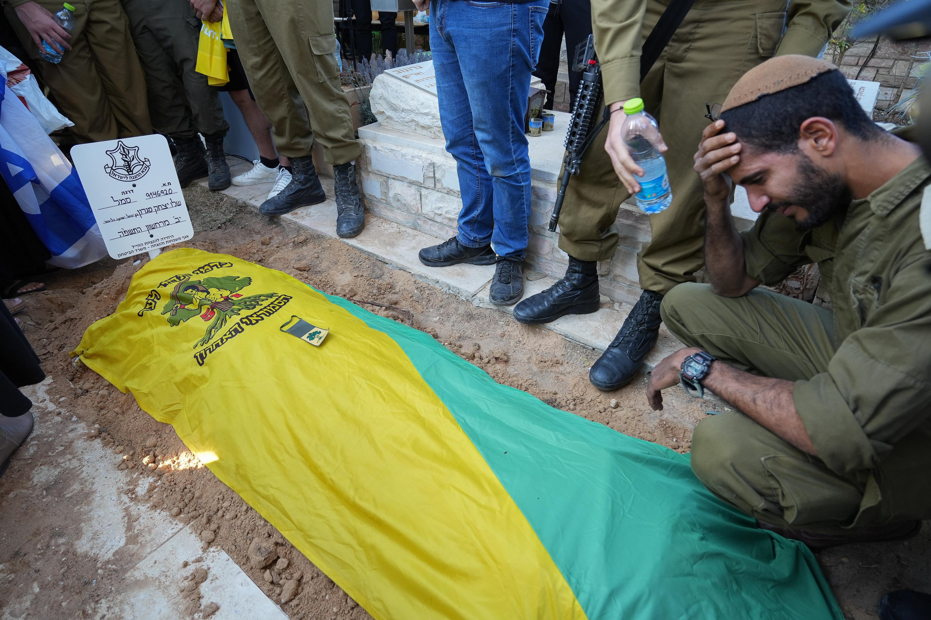 Family and friends of Israeli soldier First sergeant Nir Gofer mourn near his fresh grave after his funeral at the Military Cemetery in Sderot on November 14, 2024