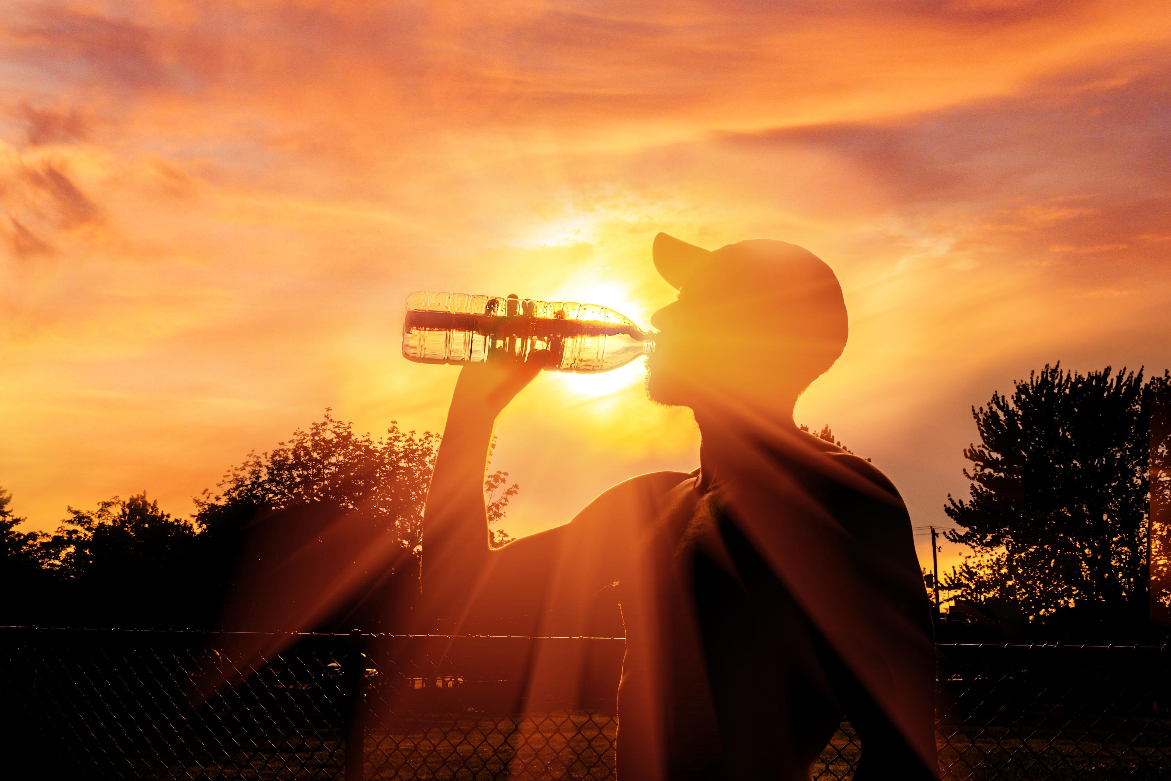 Silhouette of a man drinking water during heat wave 