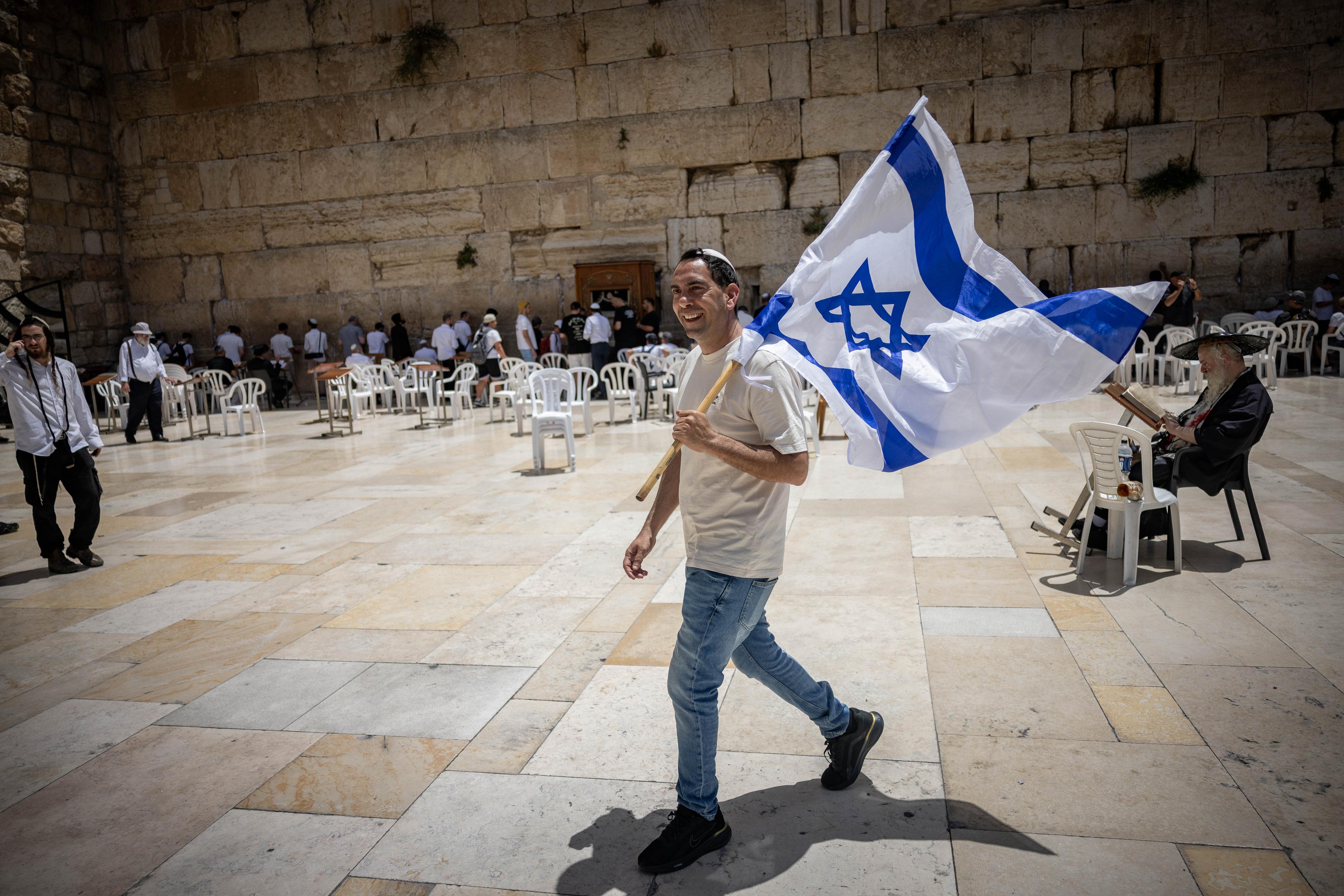 A Jewish man walking with an Israeli flag at the the Western Wall, in Jerusalem's Old City, on the morning of Jerusalem Day. May 26, 2025. 