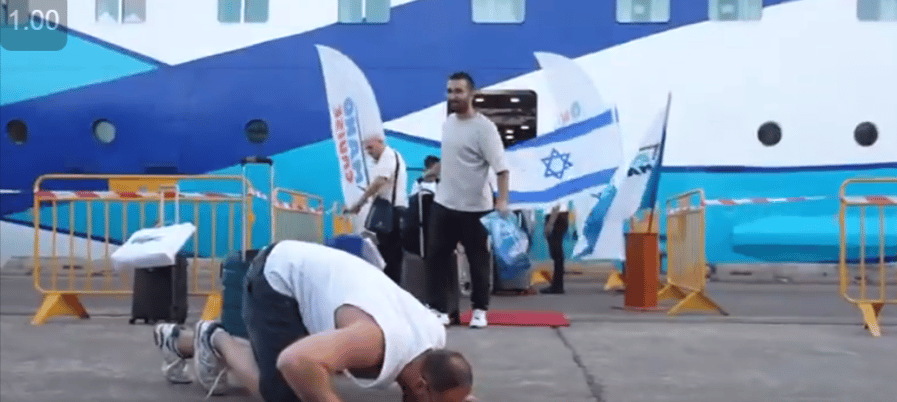 Man kissing Israeli land upon landing from evacuation ship