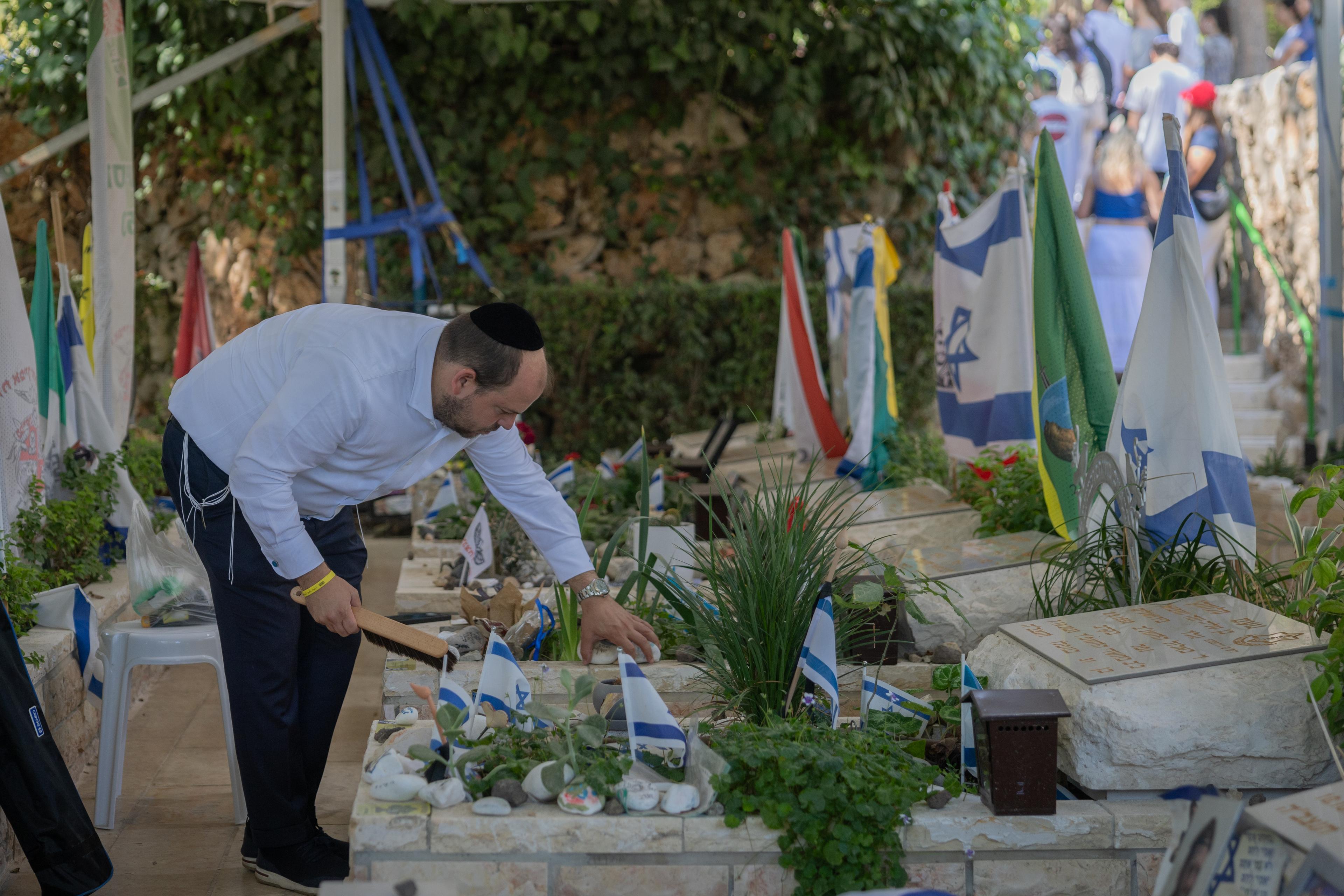 Businessman Shai Graucher cleans the grave of a fallen Israeli soldier at the military cemetery on Mount Herzl in Jerusalem, September 5, 2025. 