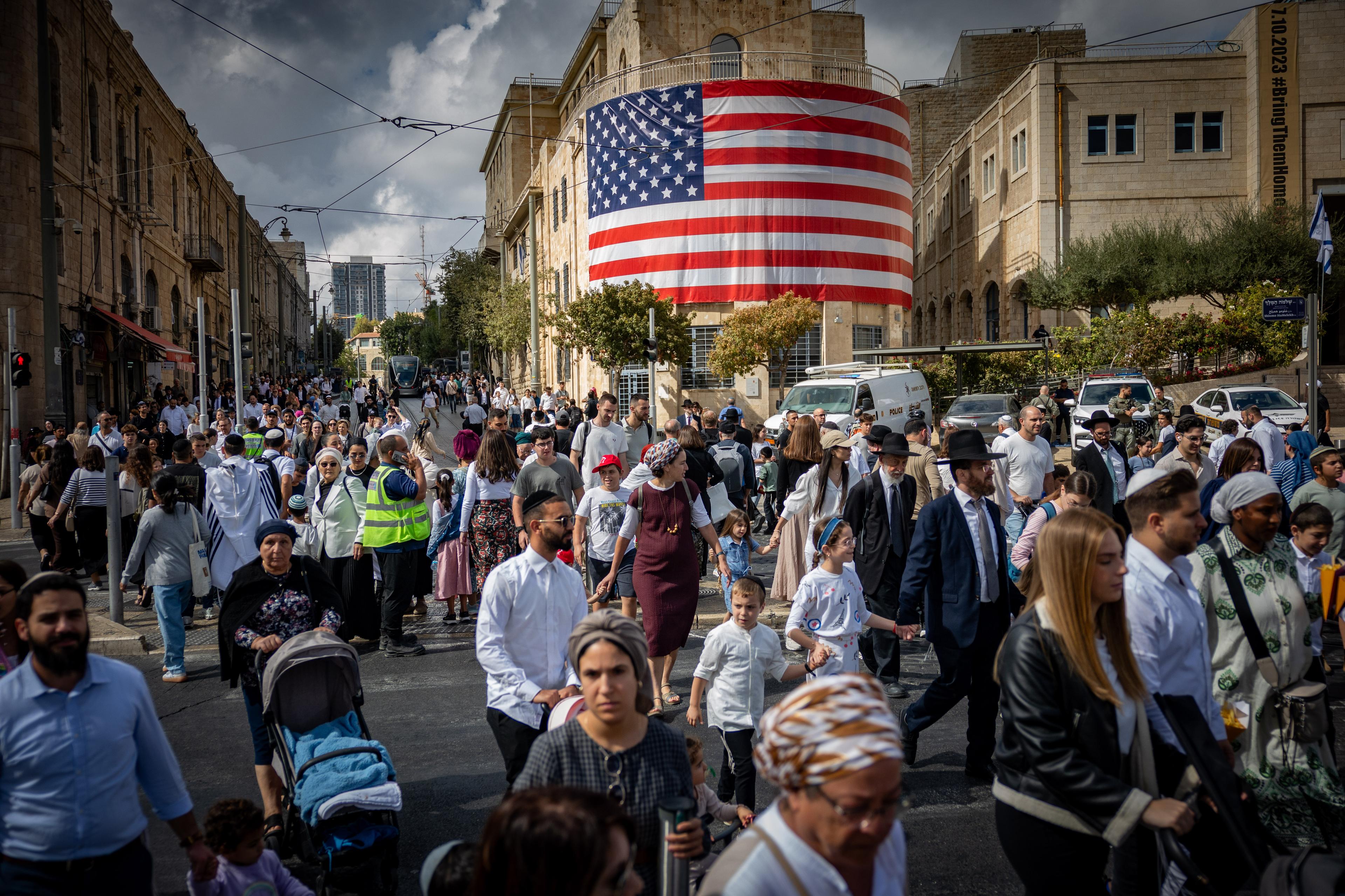 Pepole walking next to a large American flag at the Tsahal Square in Jerusalem, in honor of U.S. President Donald Trump, October 12, 2025.