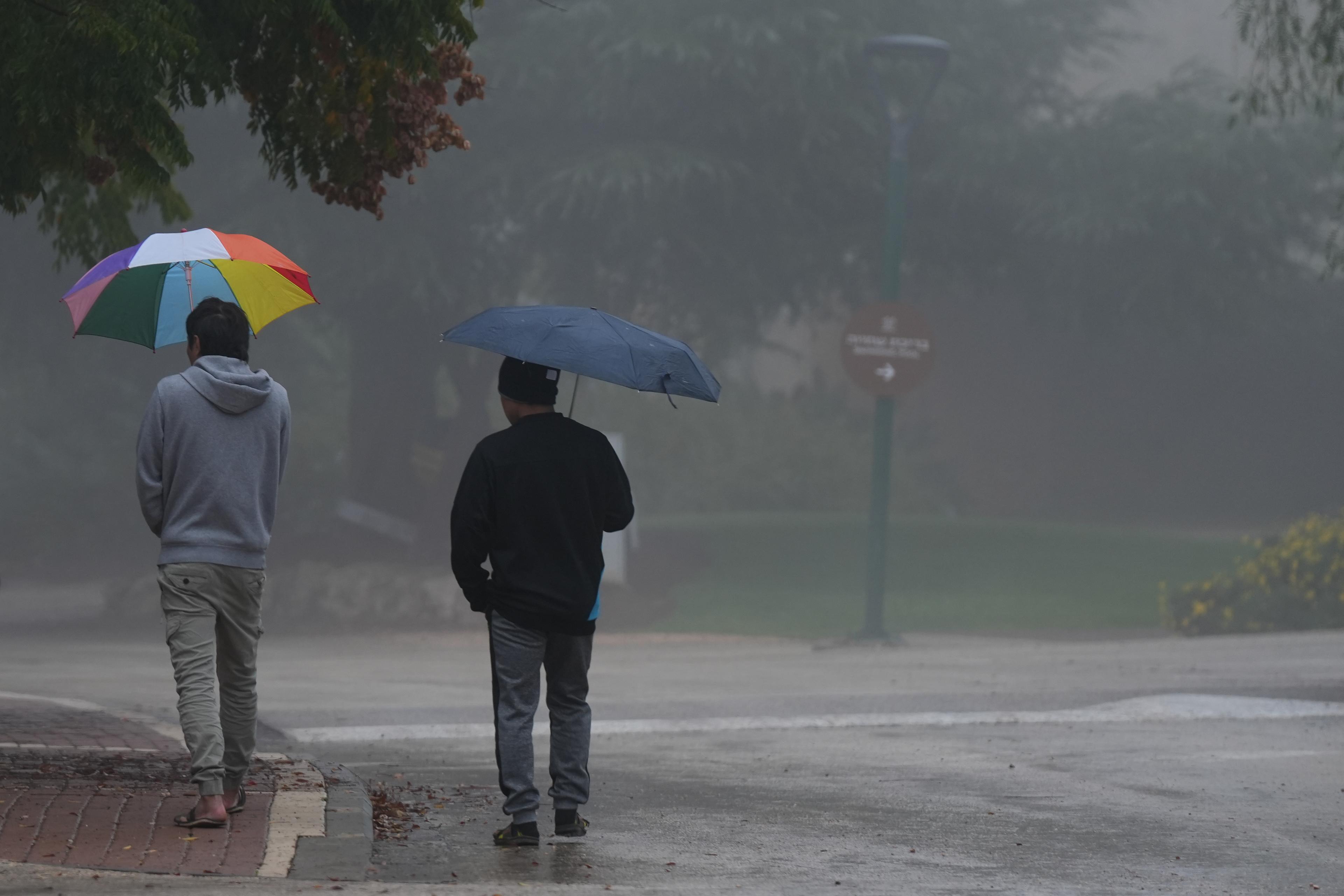 People walk on a foggy, rainy day in Kibbutz Malkia, near the border with Lebanon, on December 10, 2025.