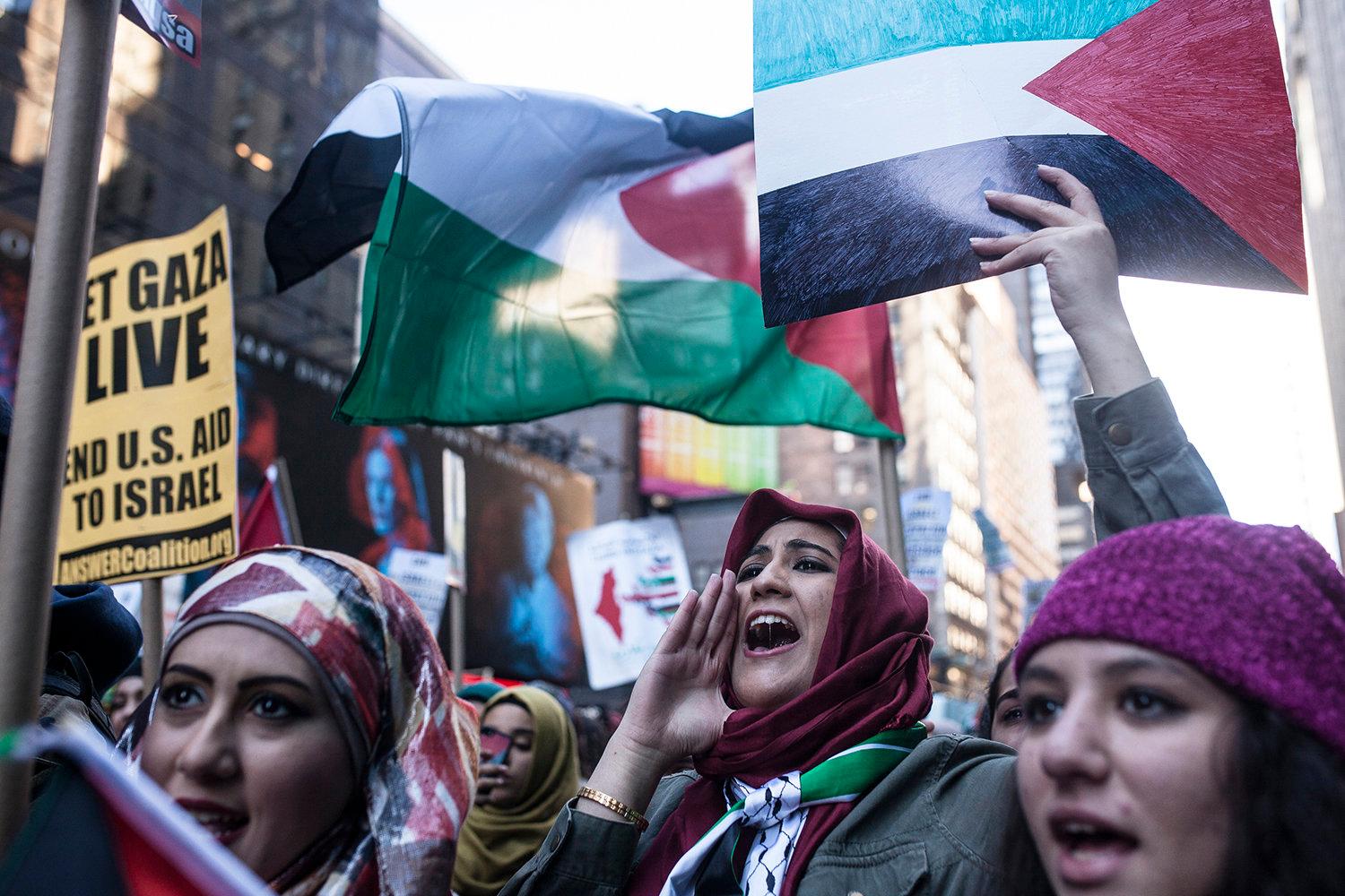 pro-Palestine demonstrators chants chant slogans and hold up signs as they march next to a Pro-Israel protest in Times Square, New york on October 18, 2015.