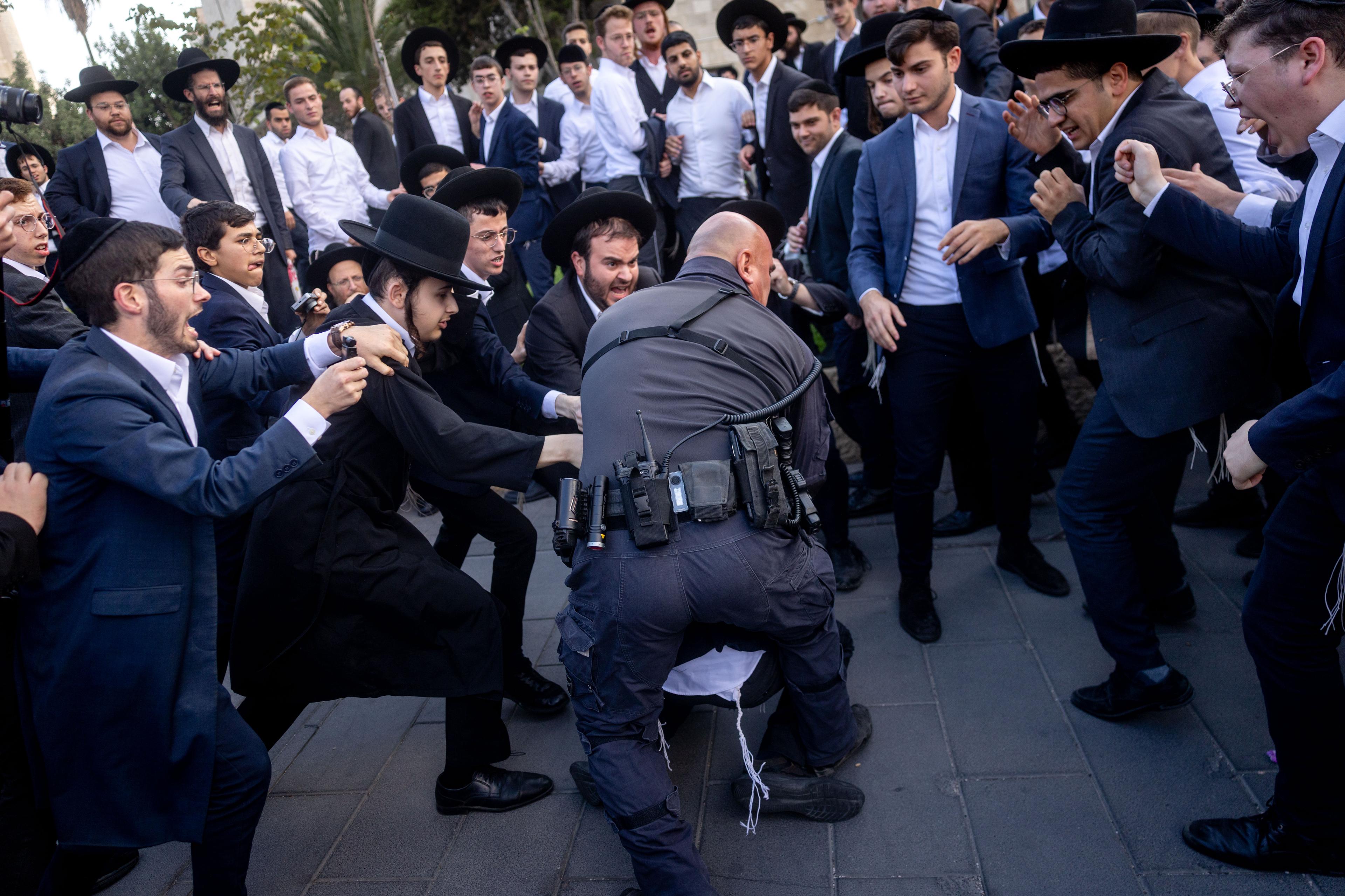 Ultra Orthodox Jewish men block a road during a protest against the jailing of Jewish seminary students who failed to comply with an army recruitment order in Jerusalem on September 18, 2025.