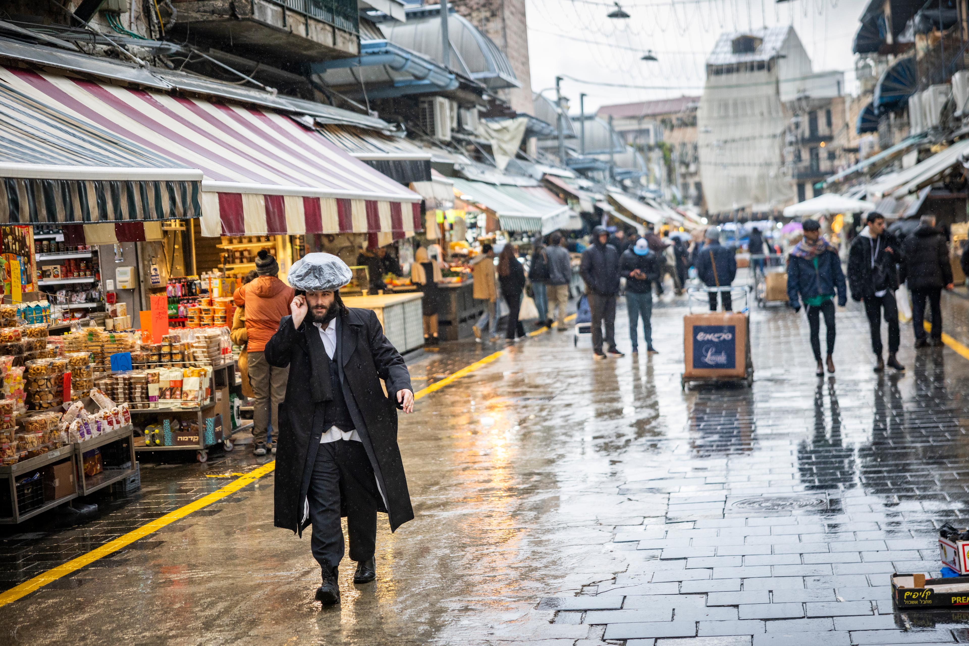 People walk in the rain at Mahane Yehuda Market in Jerusalem, December 28, 2025. 