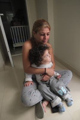 A mother hugs her child as they sit in the safe zone while a siren sounds in the town of Ashkelon